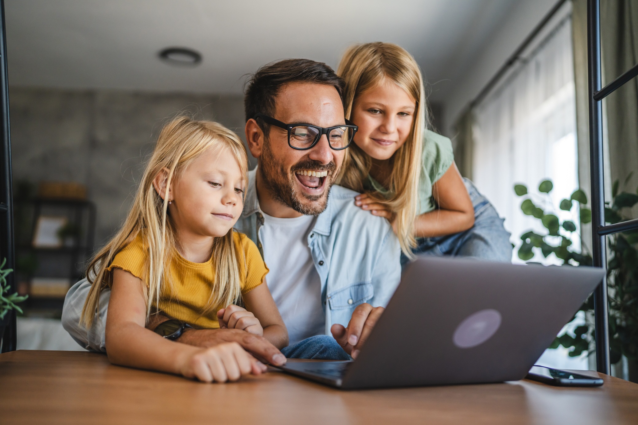 Vater mit zwei Kindern vor einem Laptop