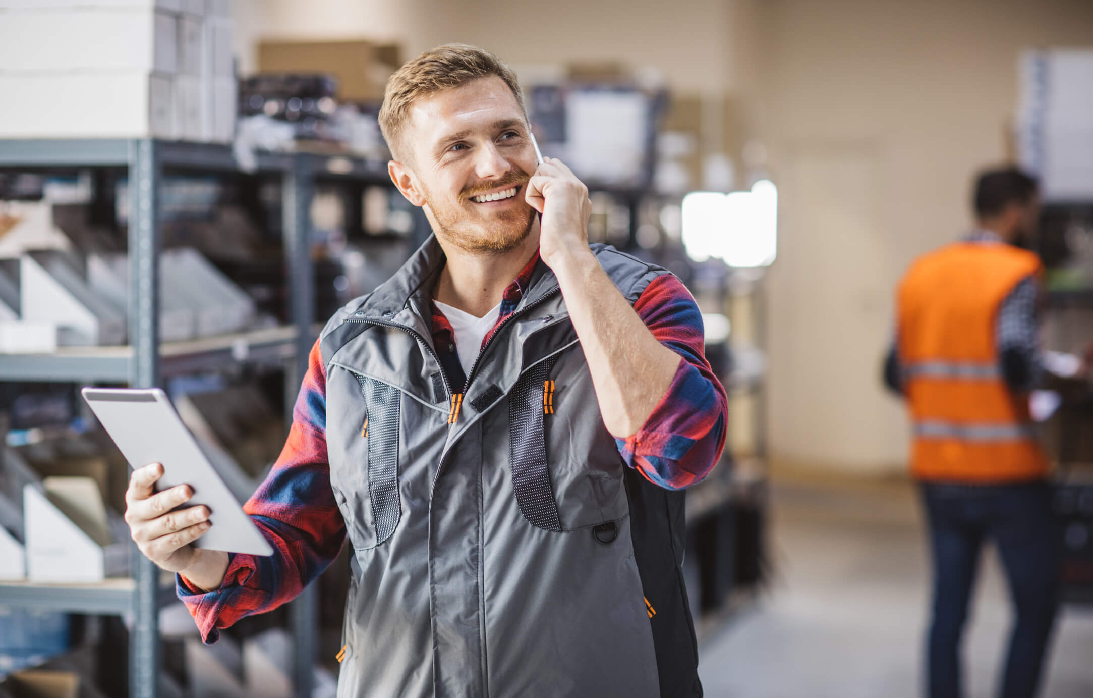 Mitarbeiter im Lager telefoniert und h&auml;lt ein Tablet