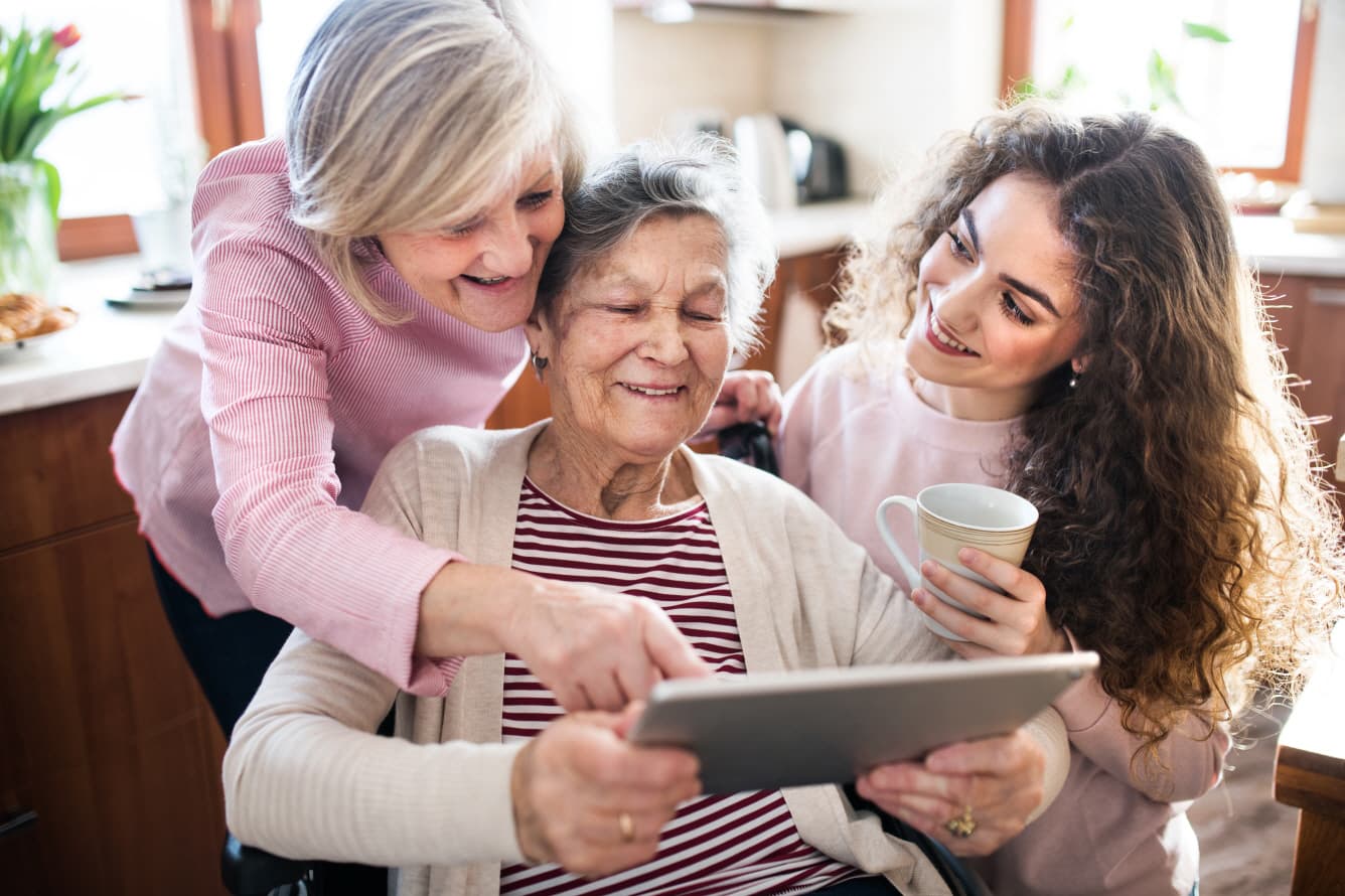 Drei Frauen verschiedener Generationen schauen zusammen auf ein Tablet