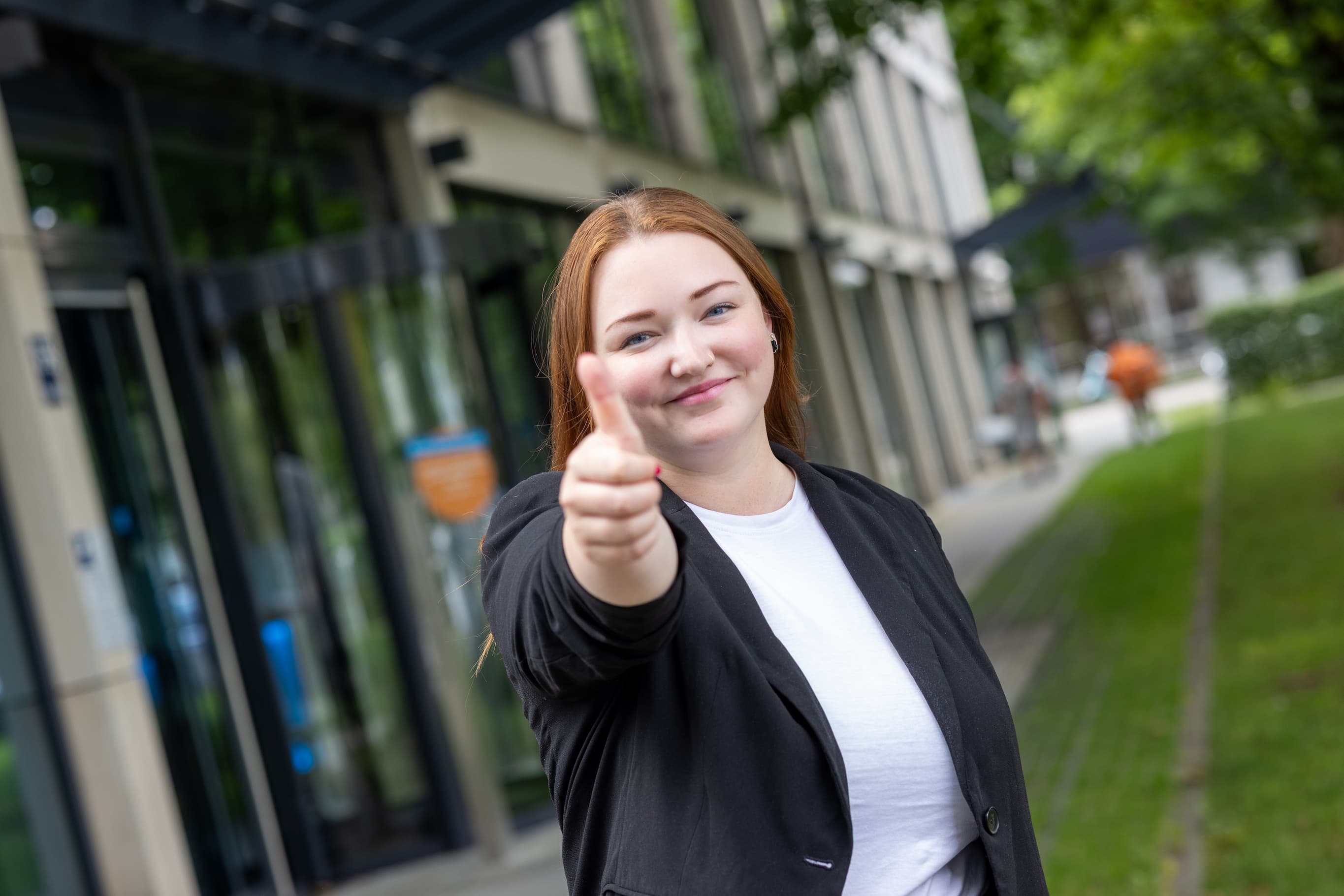 Eine Mitarbeiterin vor dem M-net-Firmensitz mit Thumbs-up