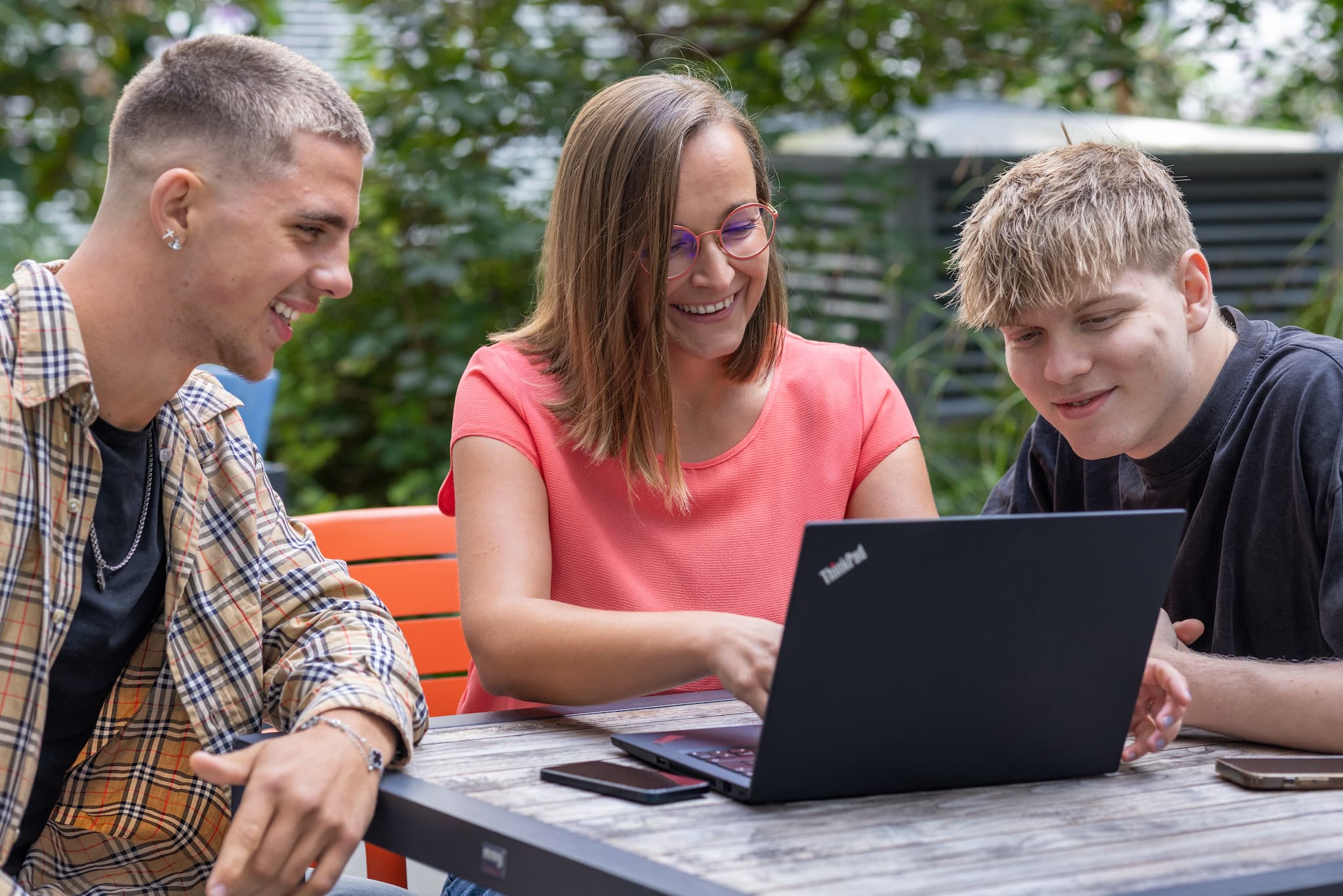 Werkstudenten im Außenbereich beim Besprechen vor einem Laptop