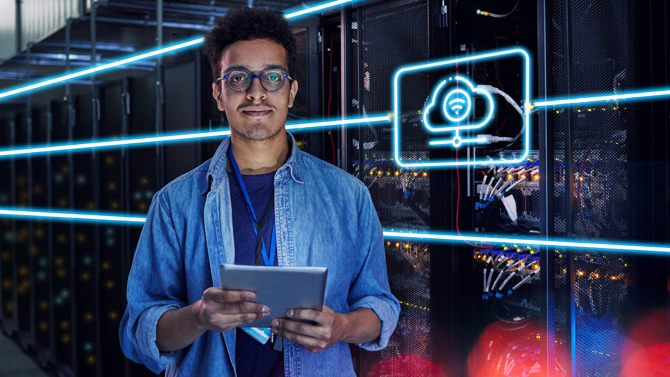 Ein Mann steht mittig im Bild und hält ein Tablet in der Hand. Im Hintergrund ist ein Rechenzentrum mit Serverschränken zu sehen. Auf dem Bild ist zudem noch ein blaues Hologramm mit einem Icon im rechten Ausschnitt zu sehen. Da Icon symbolisiert eine Cloud.