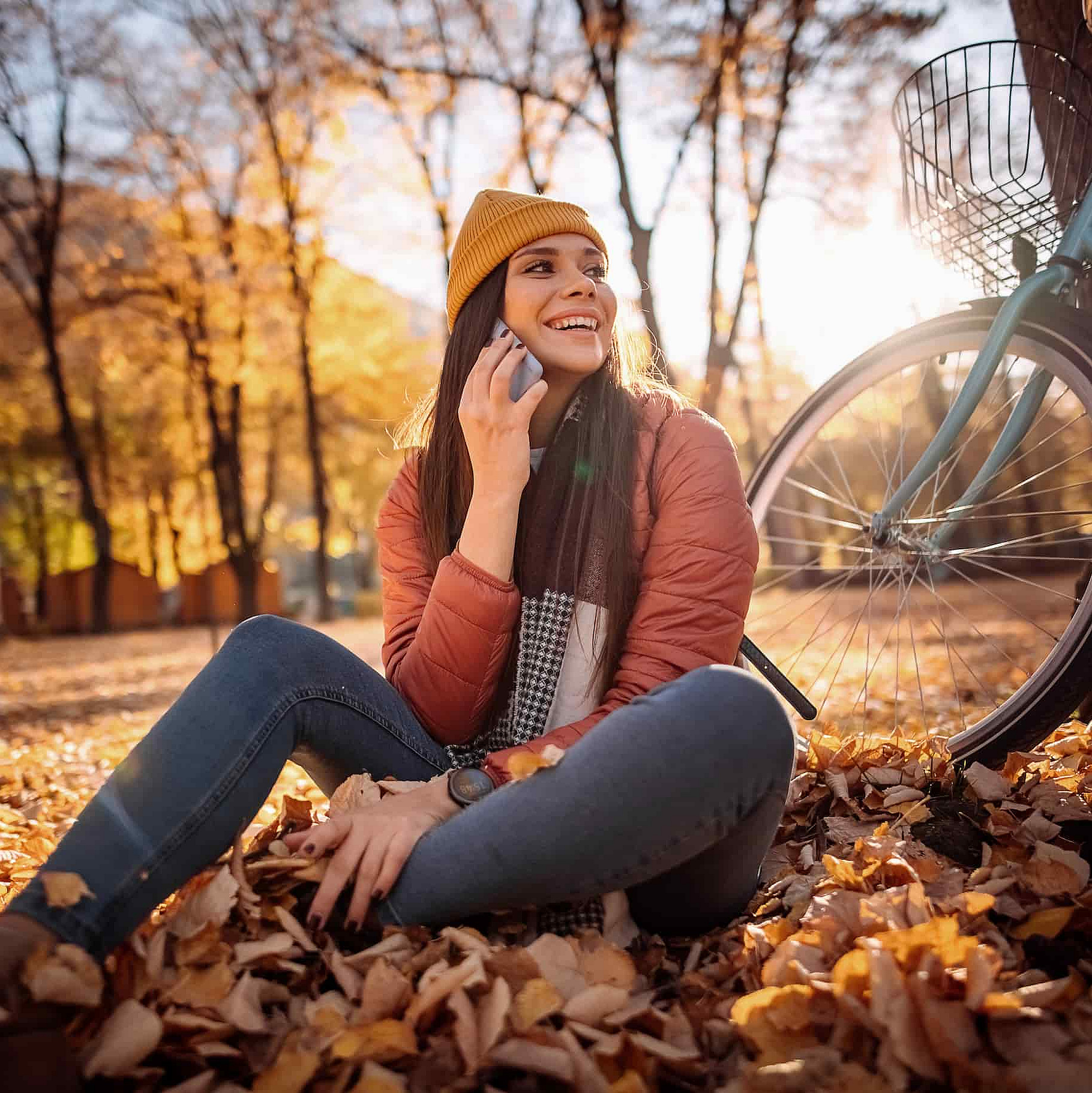 Eine Frau im Wald mit einem Handy in der Hand, ihr Fahrrad lehnt an einem Baum