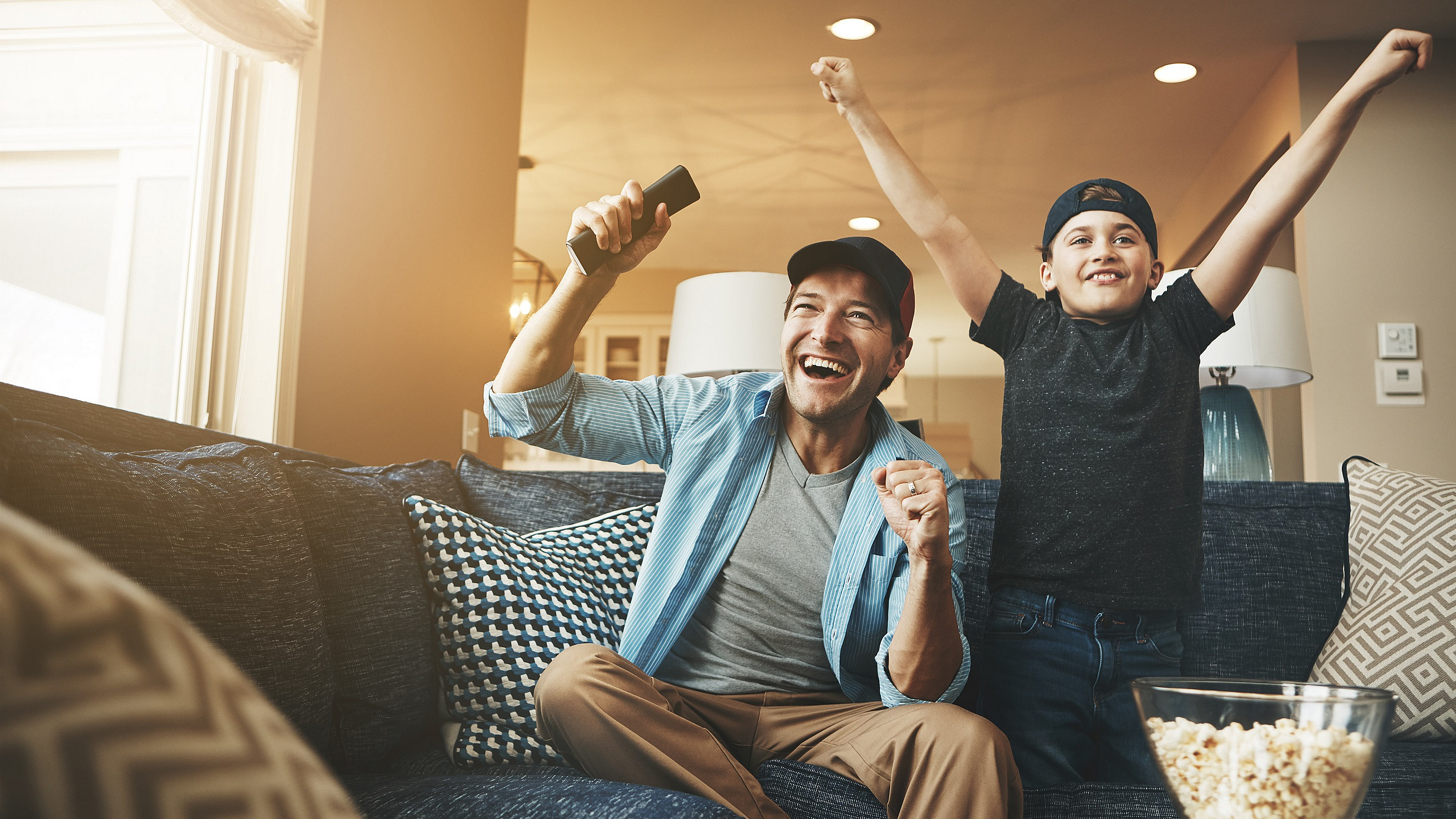 Vater und Sohn jubeln vor einem Fernsehr