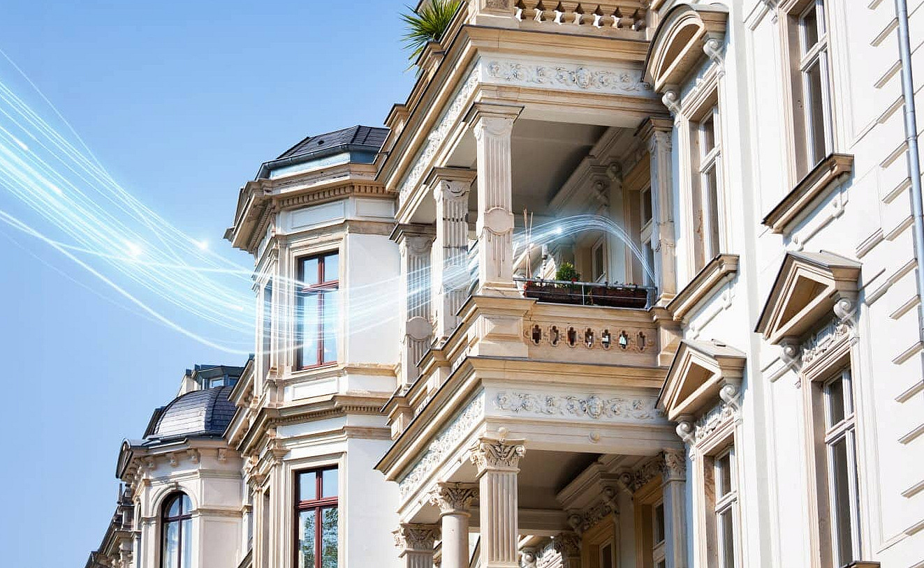 Häuserfassade, in die ein blauer stilisierter Stream hineinreicht, das Glasfaser-Signal verbildlichend