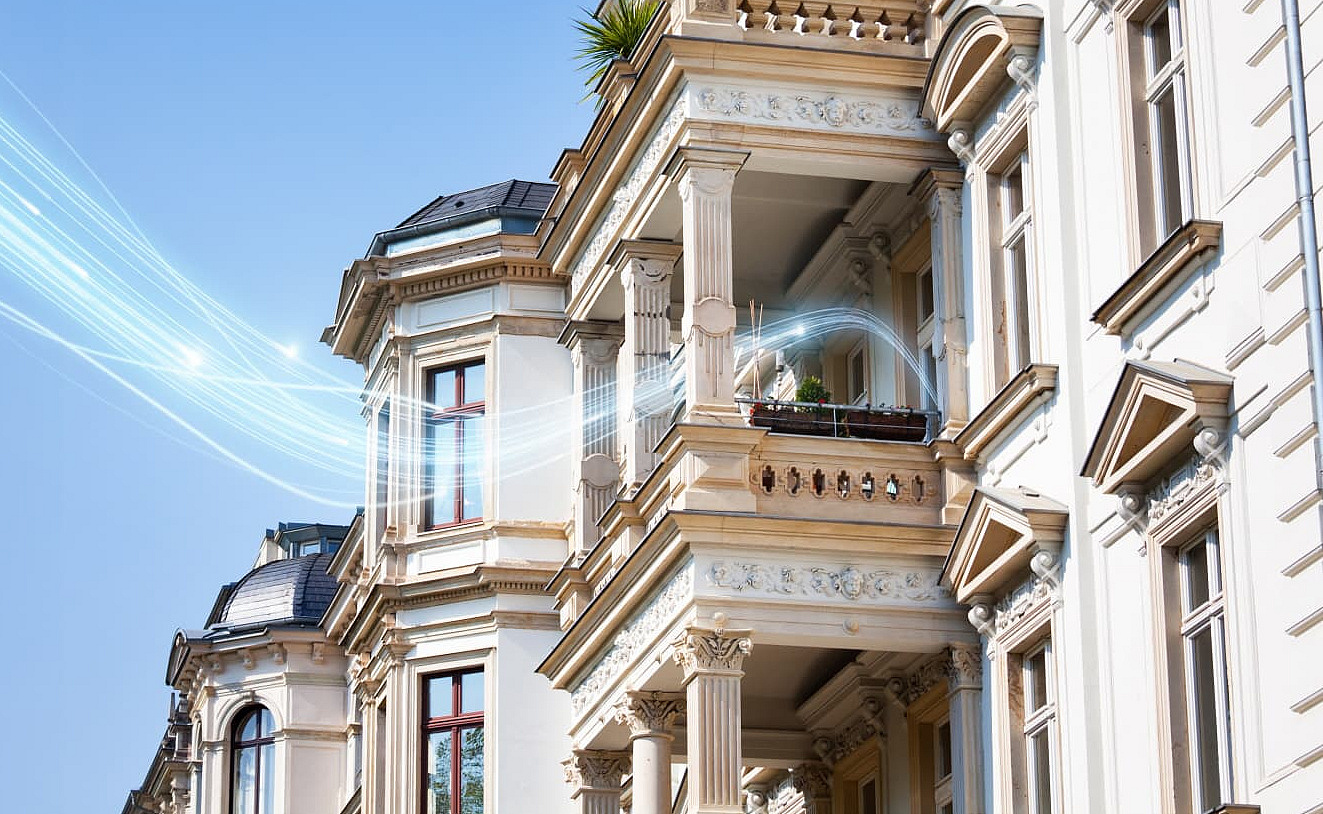 Häuserfassade, in die ein blauer stilisierter Stream hineinreicht, das Glasfaser-Signal verbildlichend