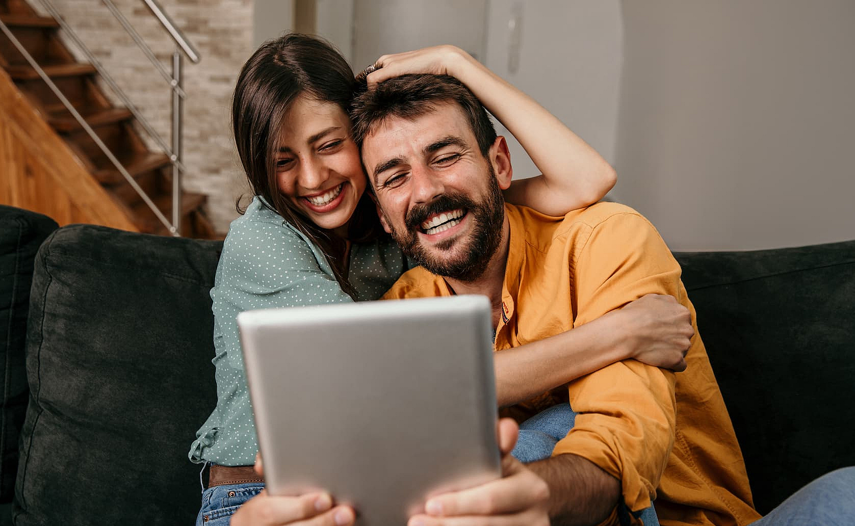 Ein paar sitzt gemeinsam zuhause und schaut in ein Tablet