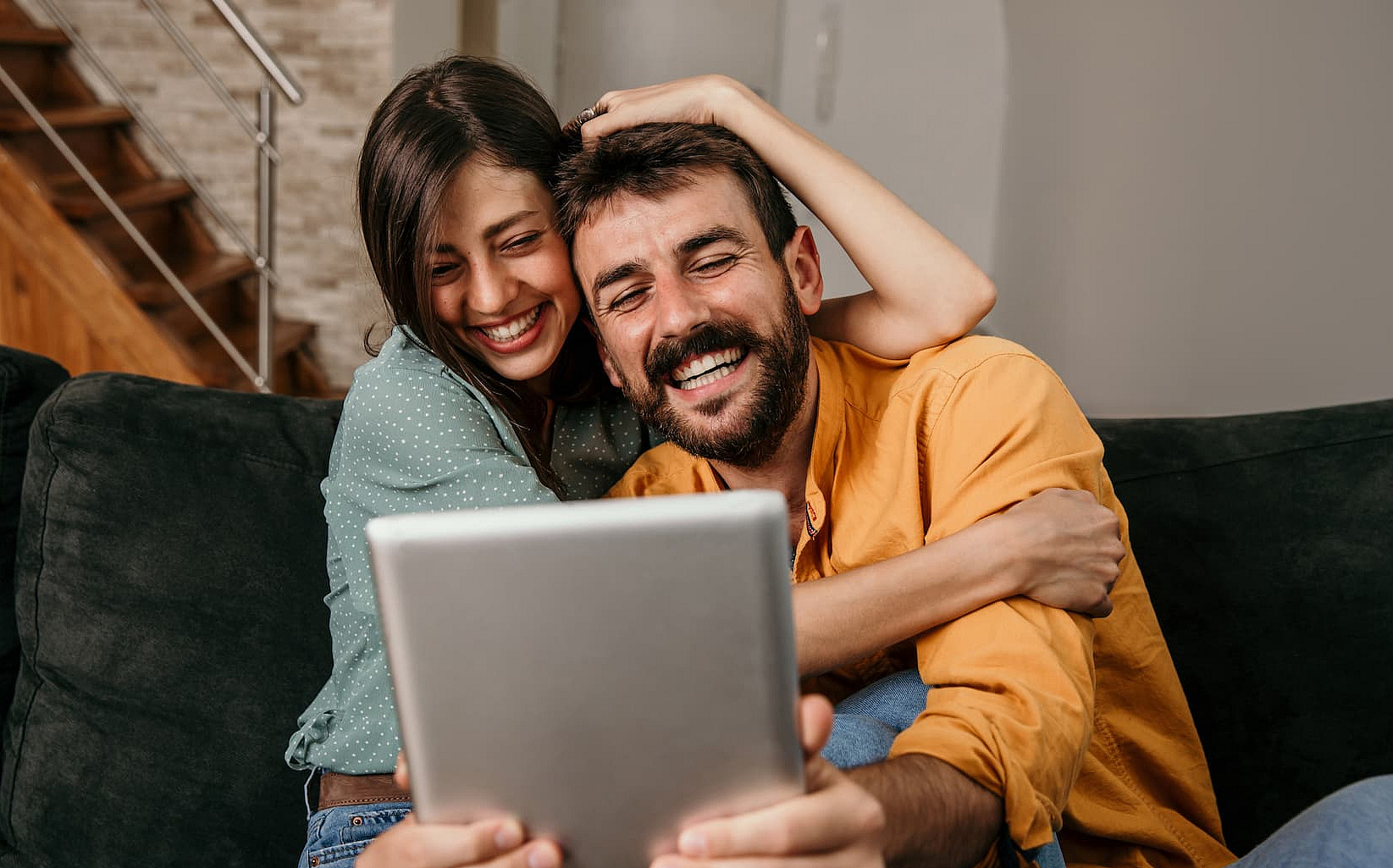 Ein Paar sitzt gemeinsam zuhause und schaut zusammen in ein Tablet