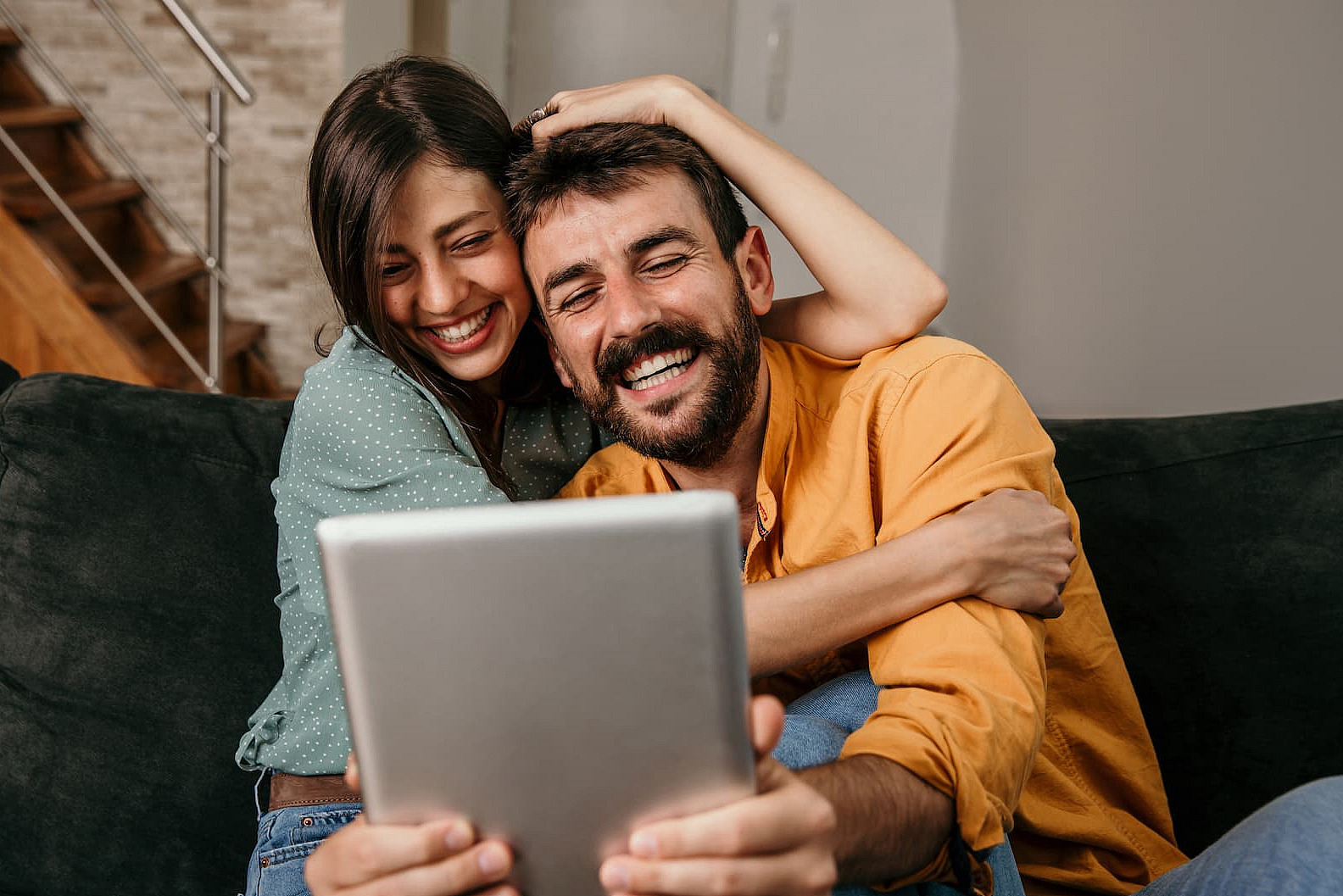Ein Paar sitzt gemeinsam zuhause vor einem Tablet