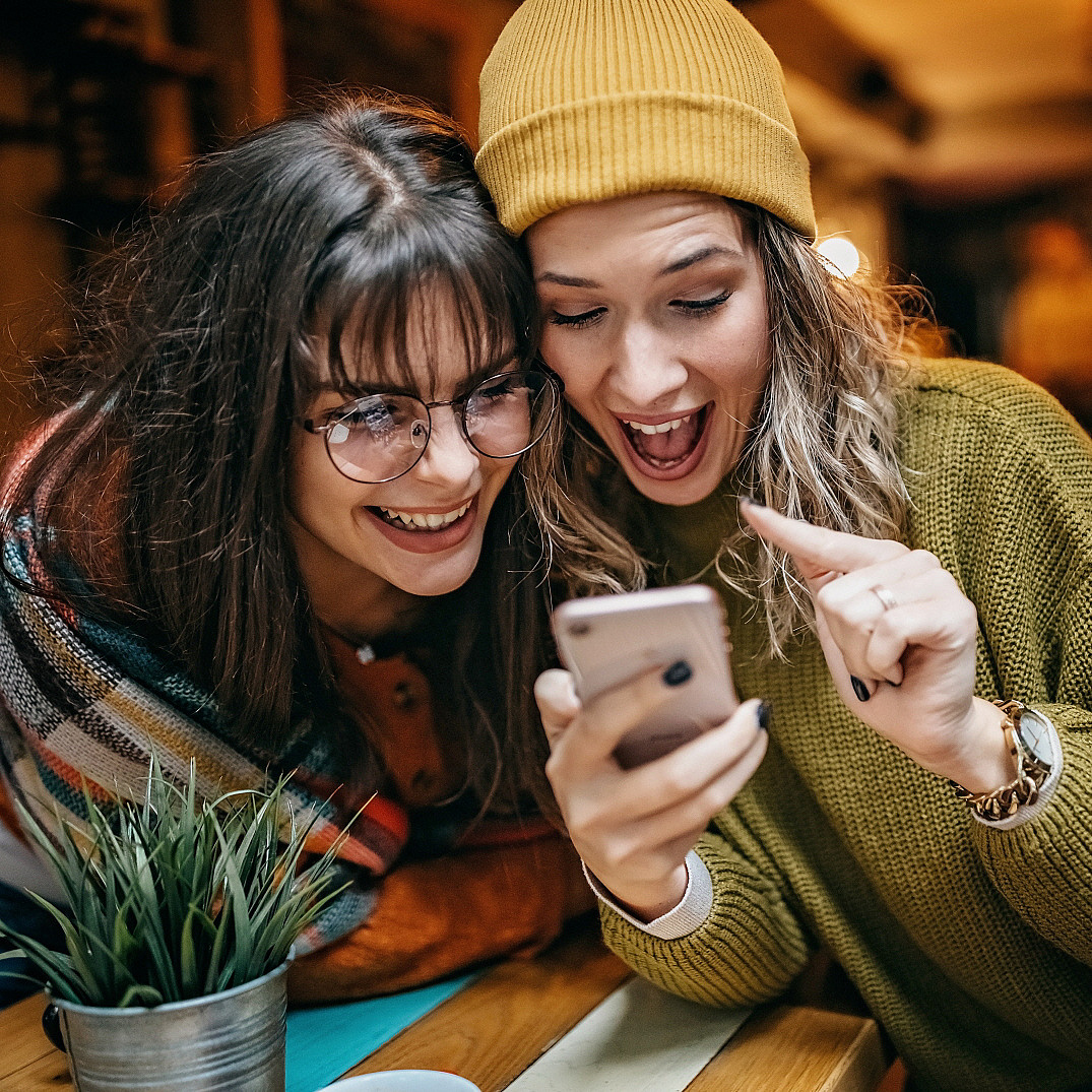 Zwei Frauen schauen gemeinsam auf ein Mobiltelefon