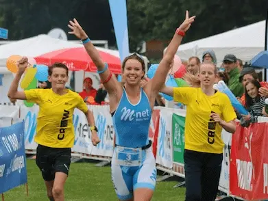 Drei Menschen laufen beim Erlanger Triathlon durch den Zielbogen.