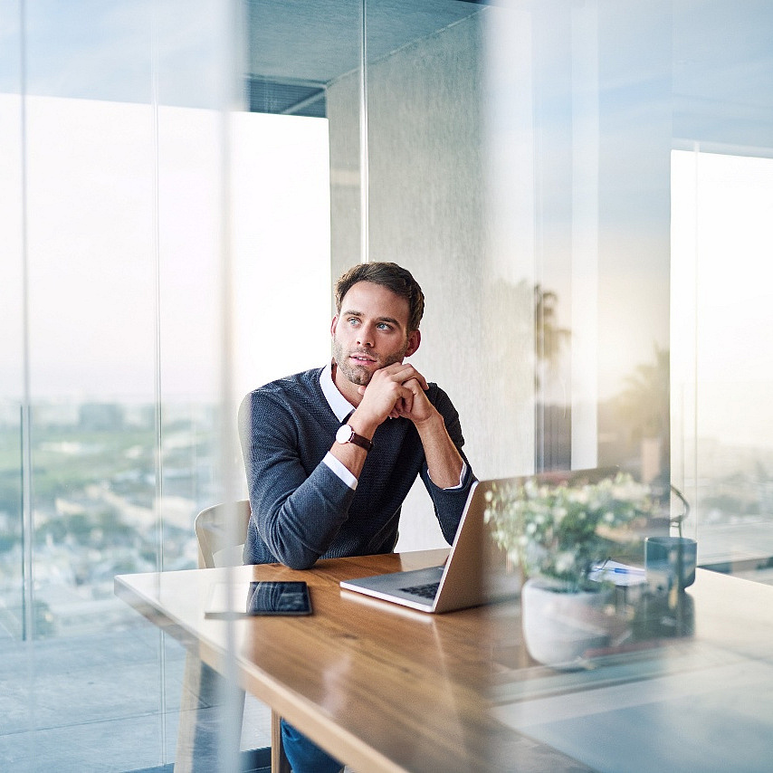Geschäftsmann sitzt an einem Tisch vor einem Laptop