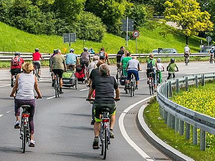 Einige Radfahrer sind zu sehen wie sie auf der Straße um eine Kurve fahren.