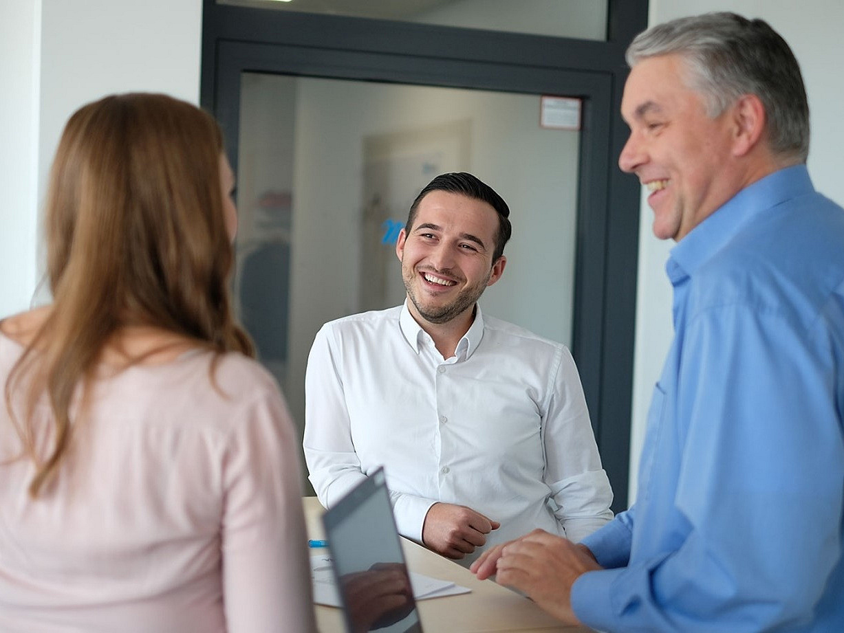 Mitarbeiter stehen gut gelaunt in einem Meeting zusammen