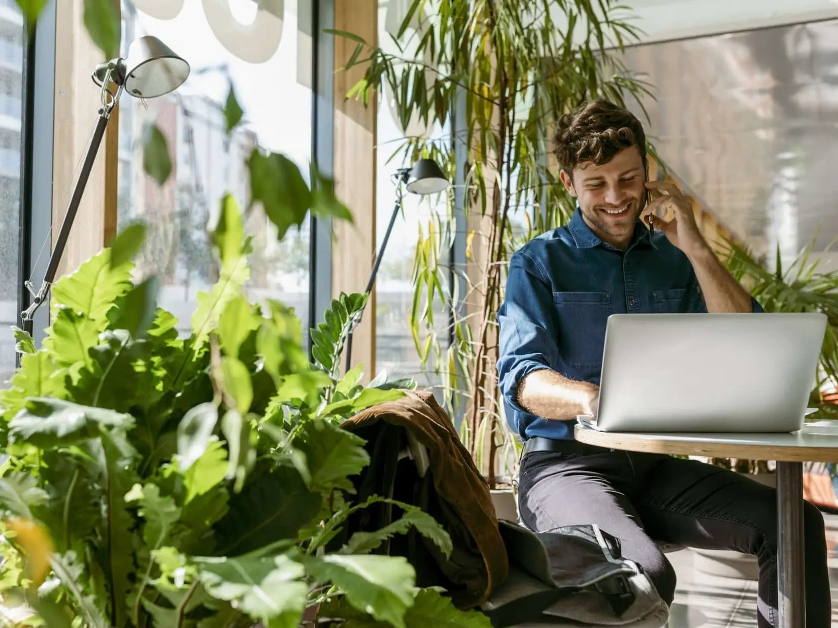 Mann sitzt vor einem Laptop und telefoniert