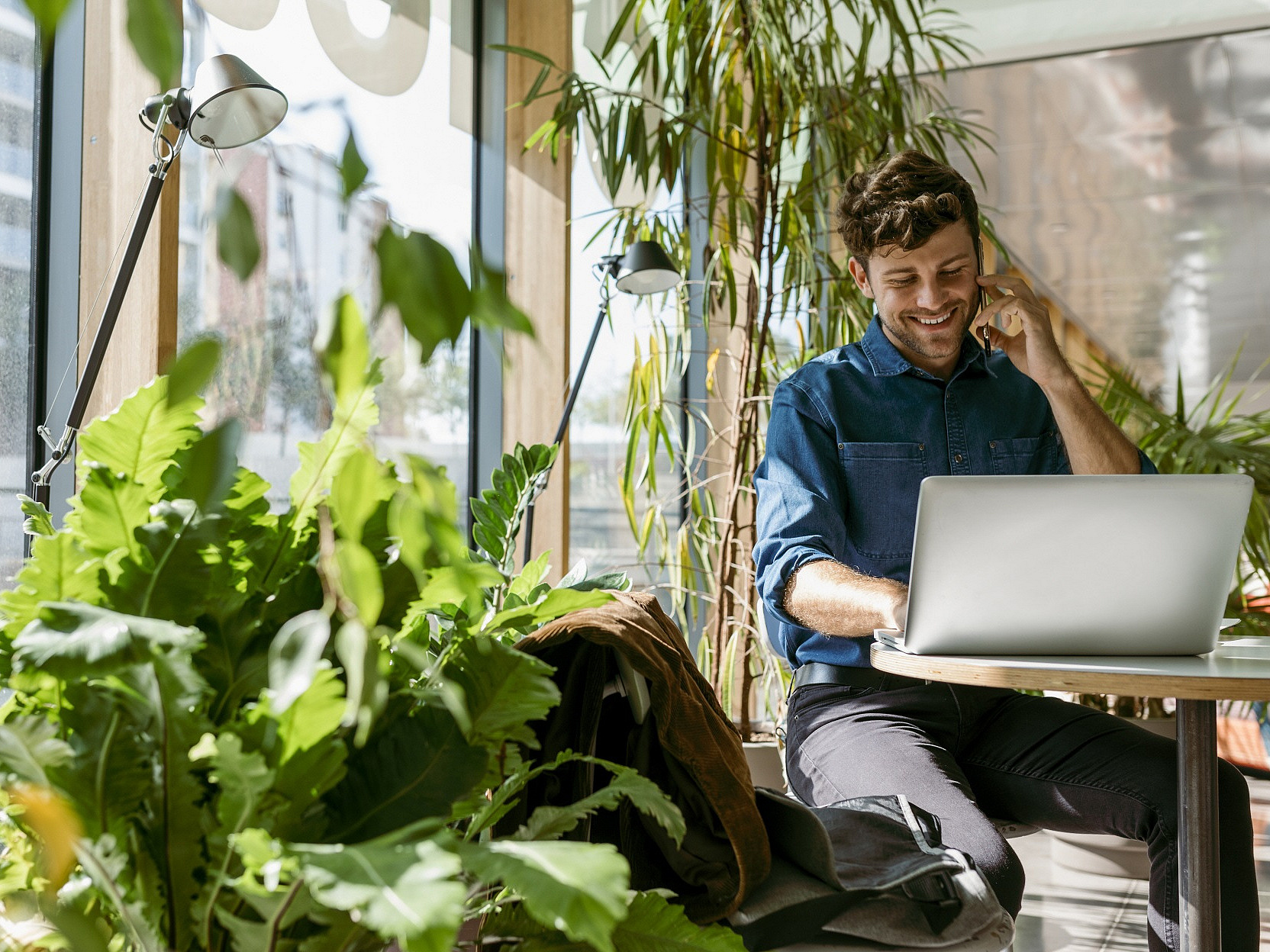 Mann sitzt vor einem Laptop und telefoniert