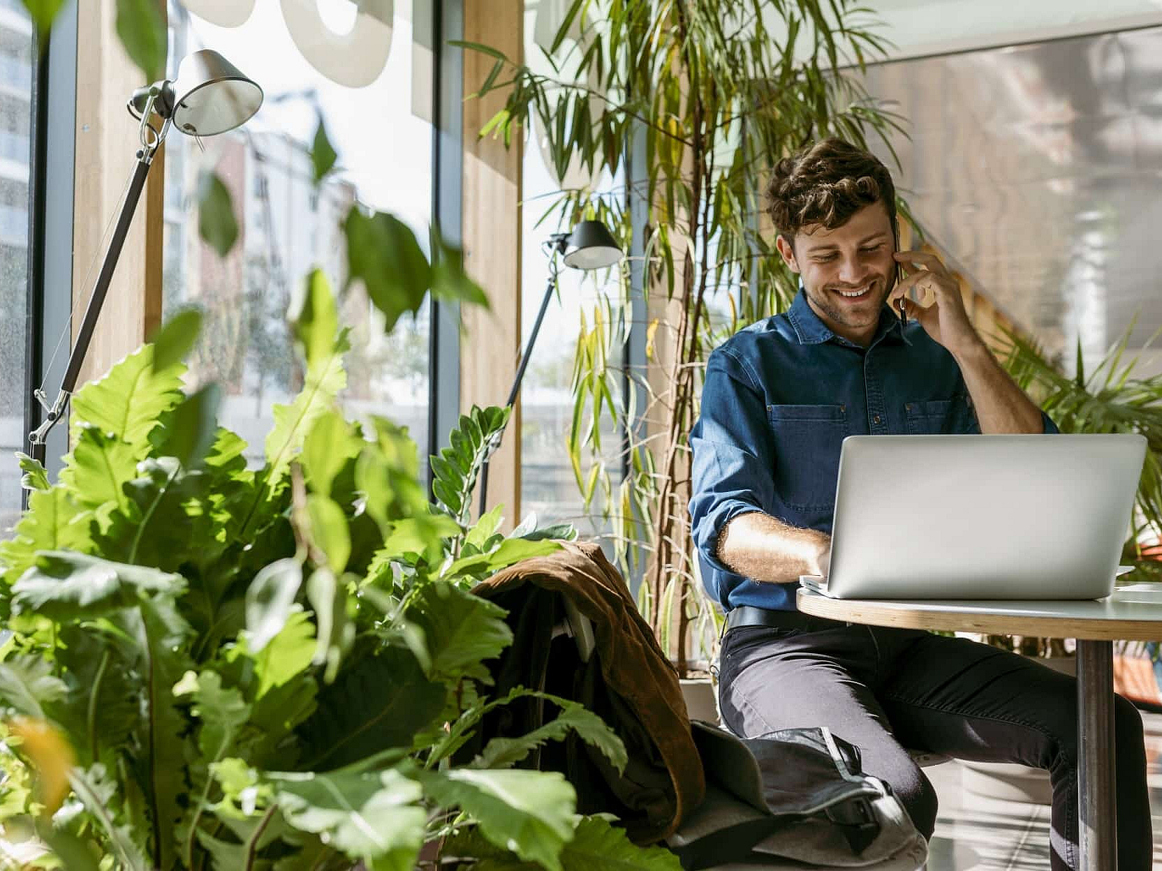 Mann sitzt vor einem Laptop und telefoniert