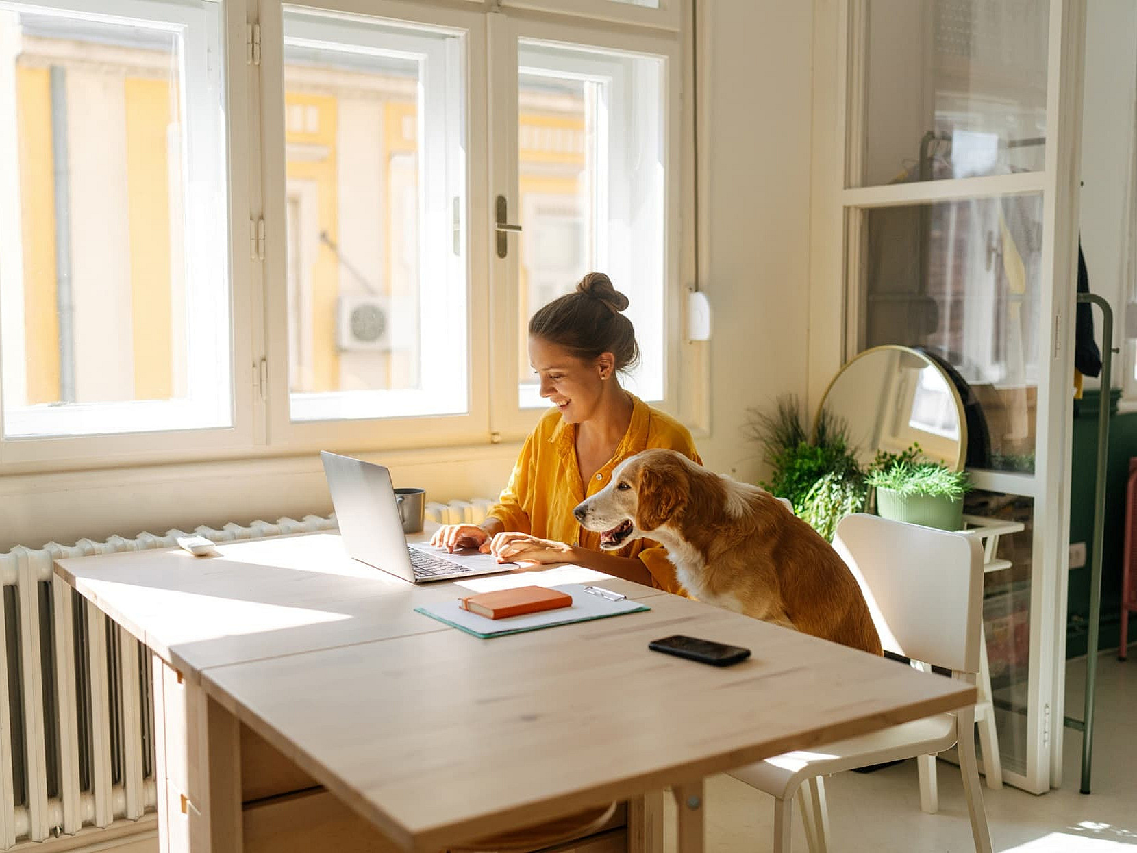 Frau sitzt am Tisch vor einem Laptop, scheinbar im Homeoffice
