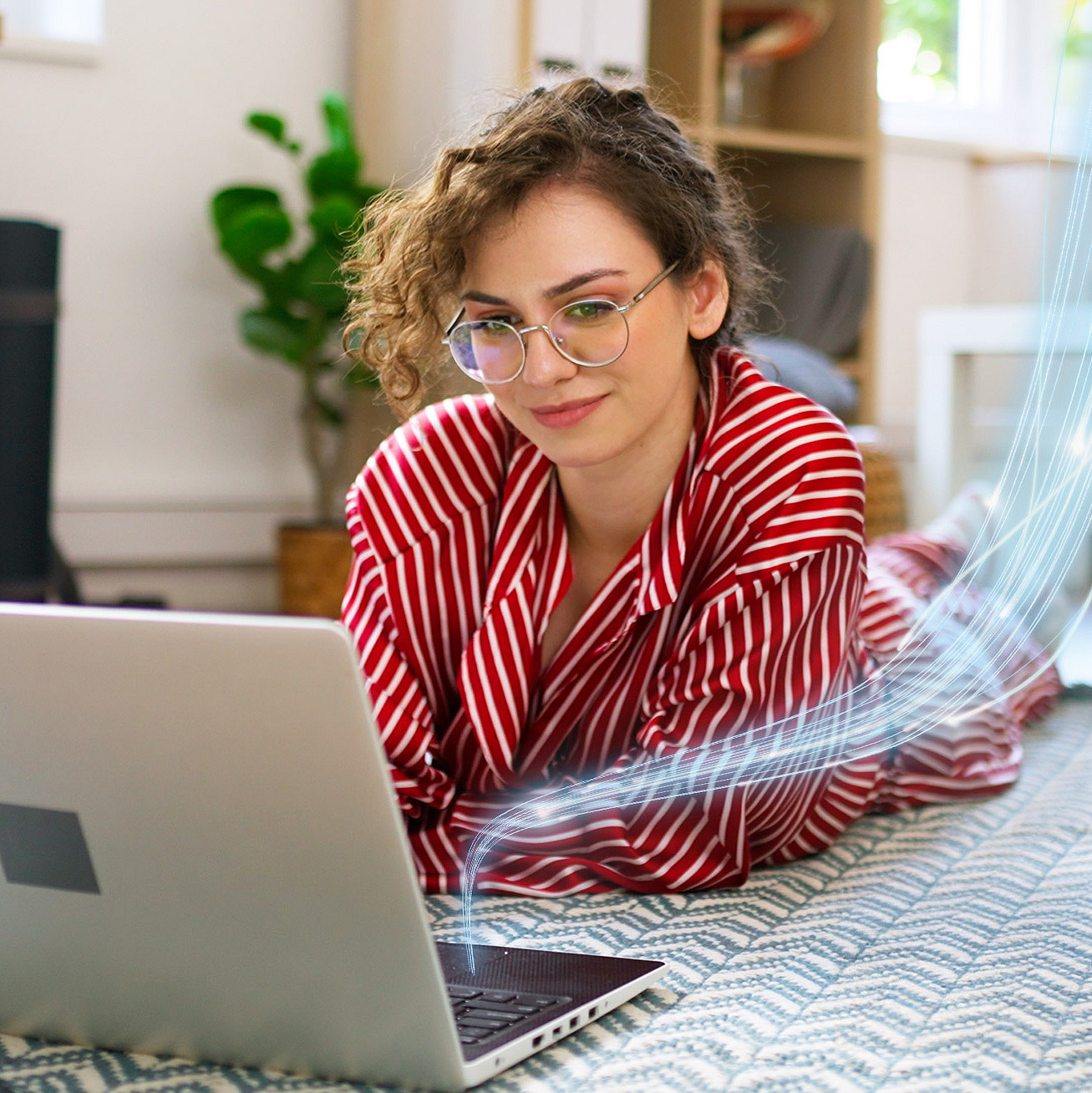 Frau liegt auf dem Boden und arbeitet an einem Laptop
