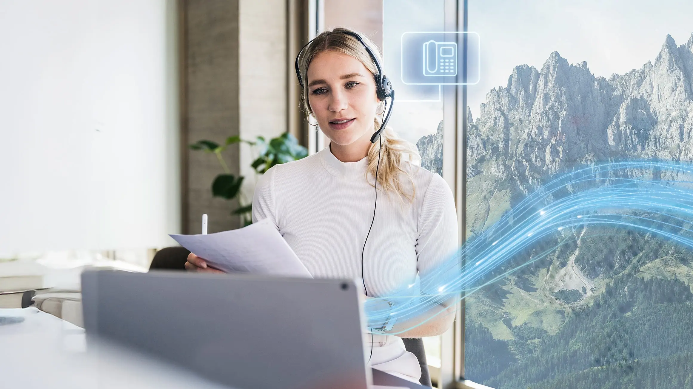 Mitarbeiterin im Support-Team nutzt digitale Telefonie im Büro mit Alpenblick