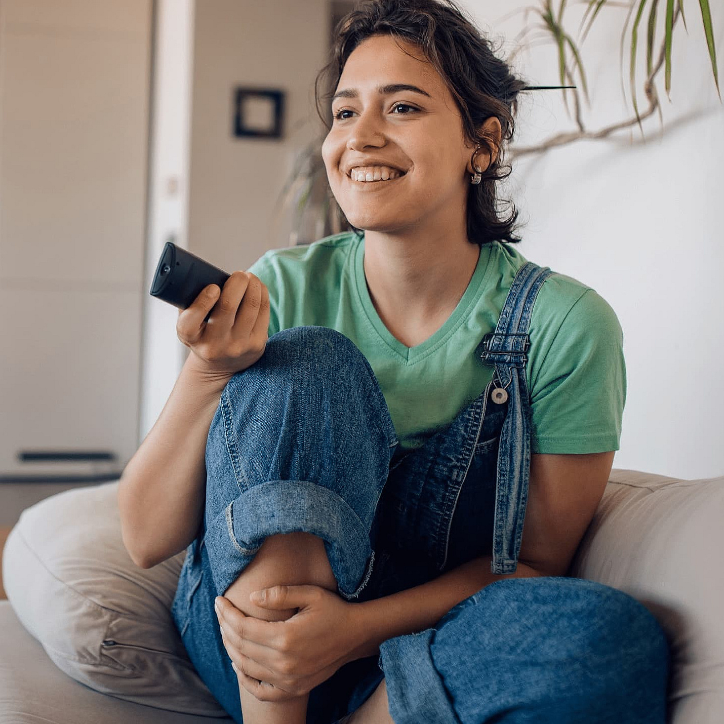 Frau auf dem Sofa mit einer TV Fernbedienung in der Hand
