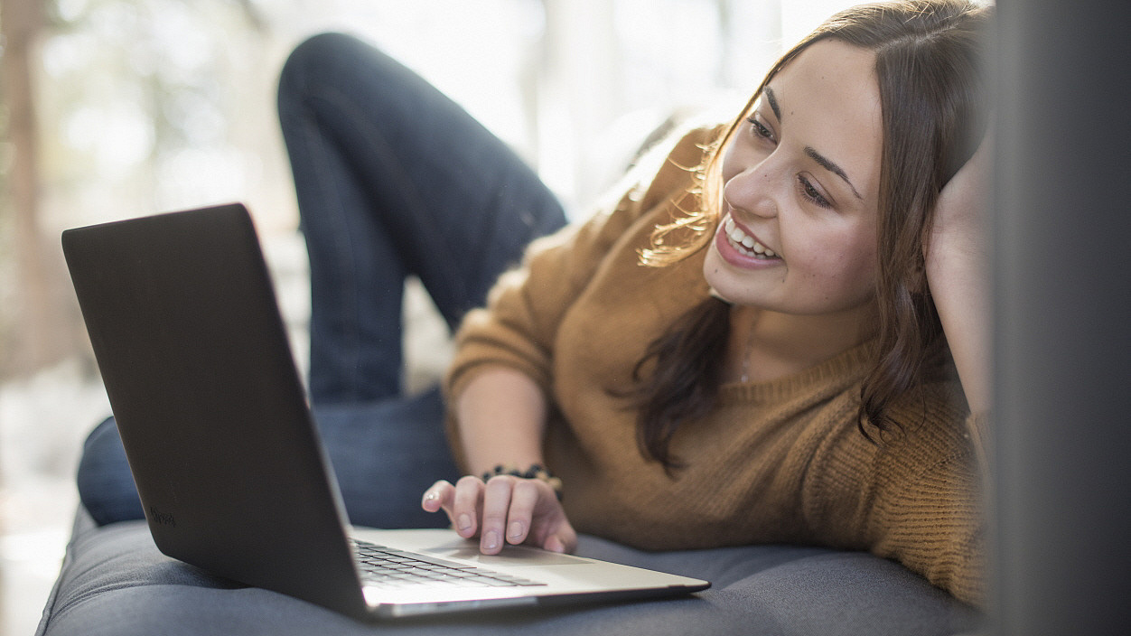 Frau liegend vor Laptop