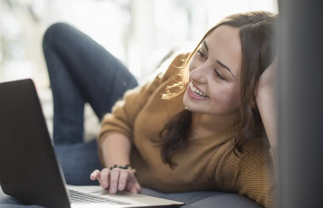 Eine Frau liegend vor ihrem aufgeklappten Laptop
