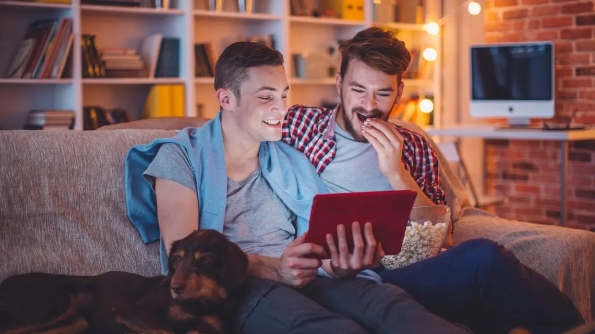 Zwei M&auml;nner auf dem Sofa sehen sich gemeinsam etwas auf einem iPad an