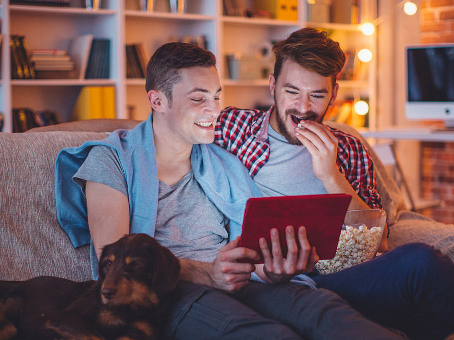 Zwei M&auml;nner auf dem Sofa vor einem Tablet