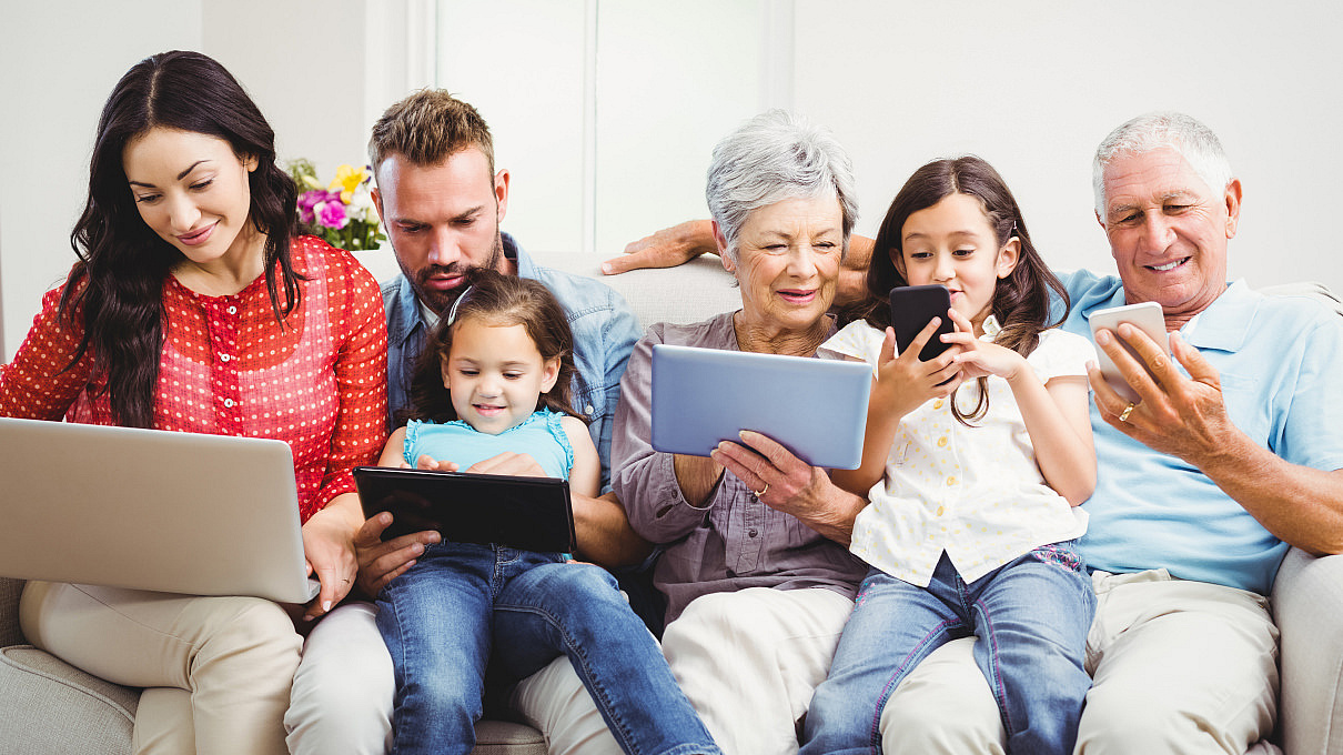 Familie mit iPad und Laptops sehen sich gemeinsam etwas im Internet an