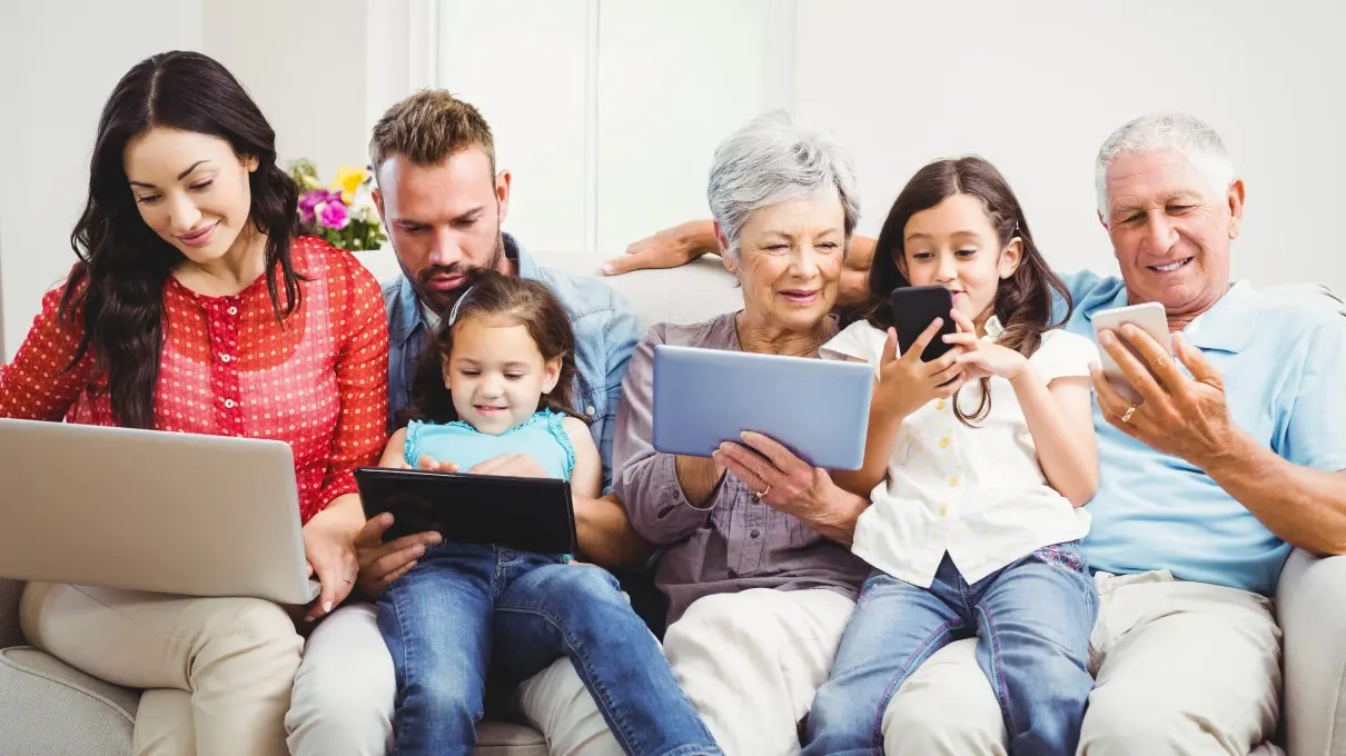 Familie mit iPad und Laptops sehen sich gemeinsam etwas im Internet an