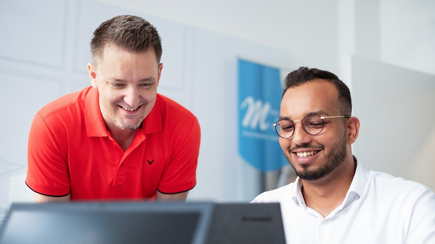 Zwei Mitarbeiter vor einem Bildschirm