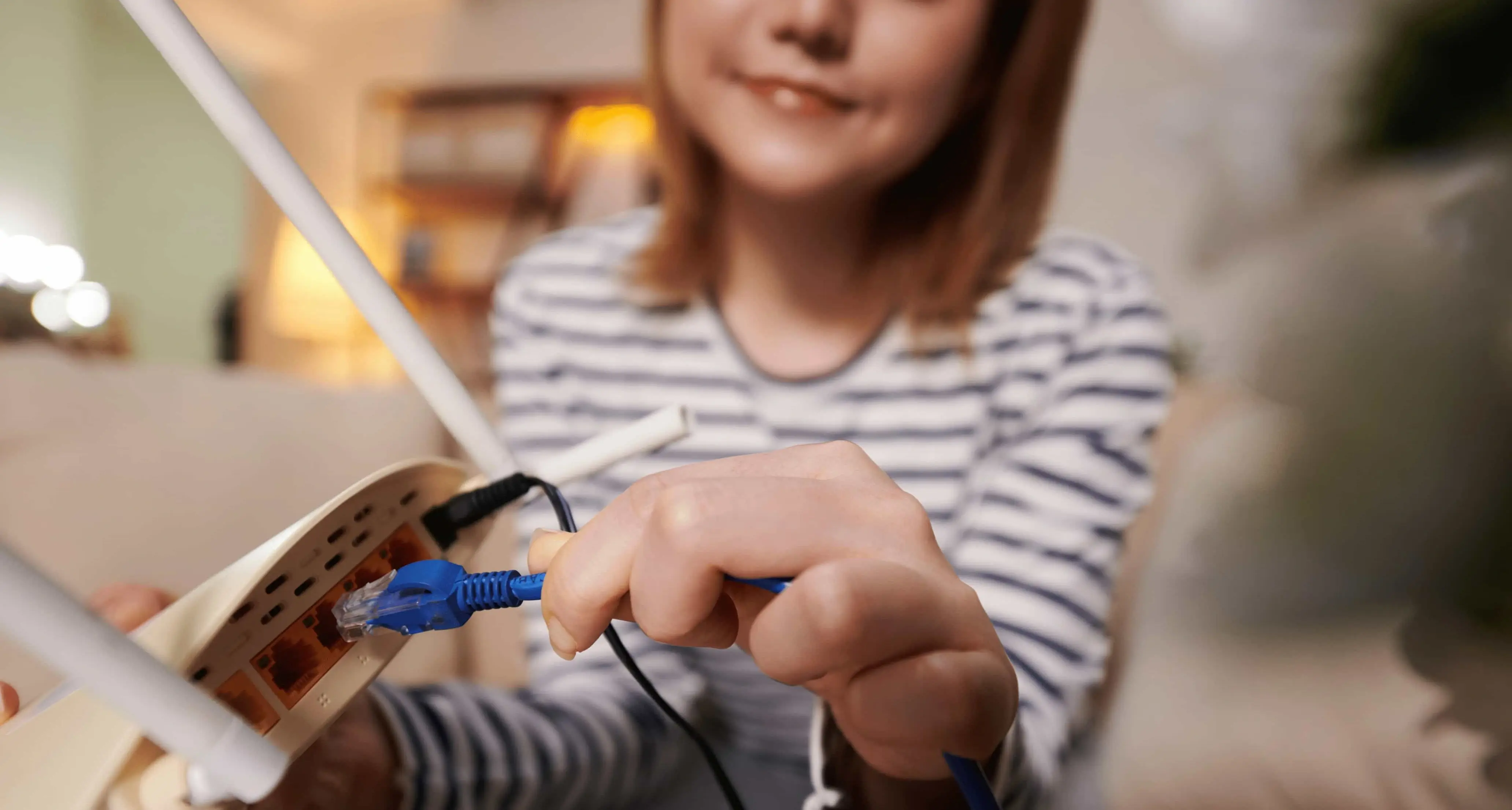 Eine Frau steckt ein LAN-Kabel in einen Router