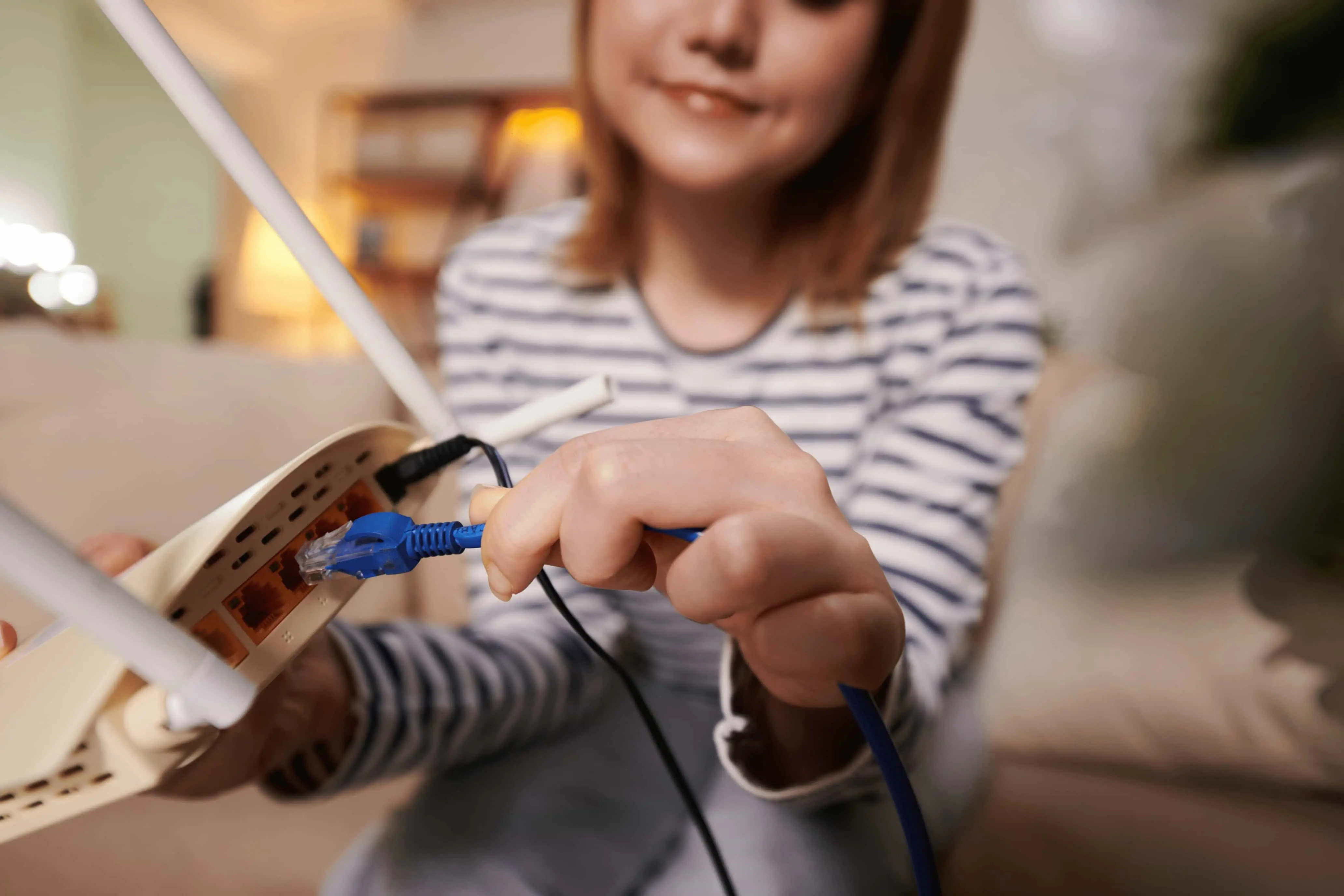 Eine Frau in Großaufnahme steckt ein Kabel in einen Router