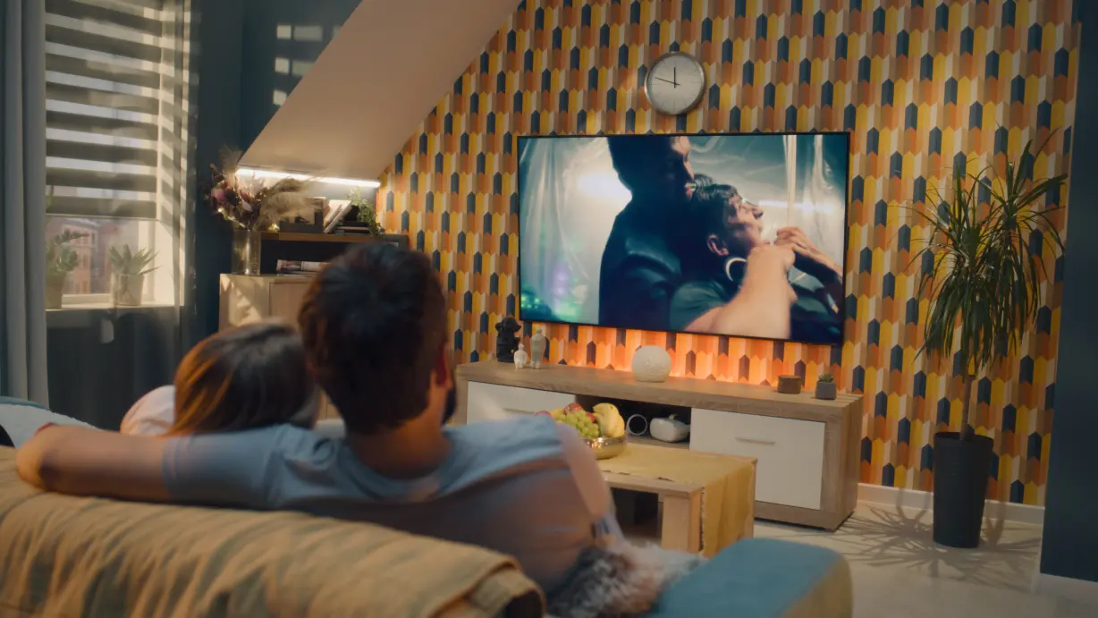 Blick von hinten auf ein Paar auf dem Sofa, die vor dem Fernseher sitzen