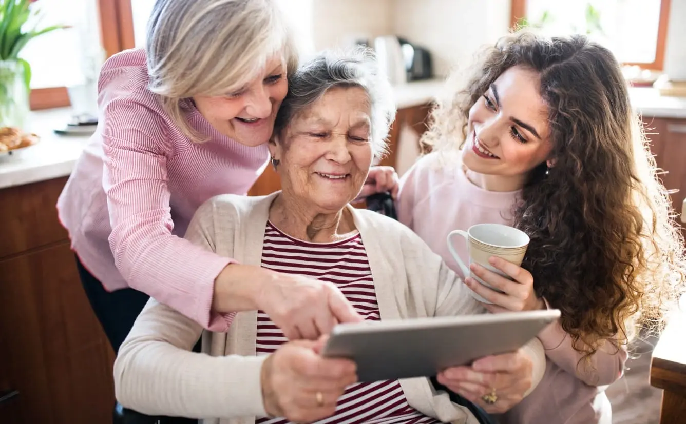 Drei Frauen verschiedener Generationen schauen gemeinsam in ein Tablet