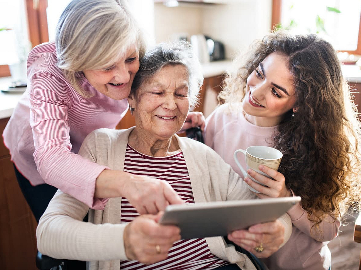 Zwei Seniorinnen mit Frau vor einem iPad