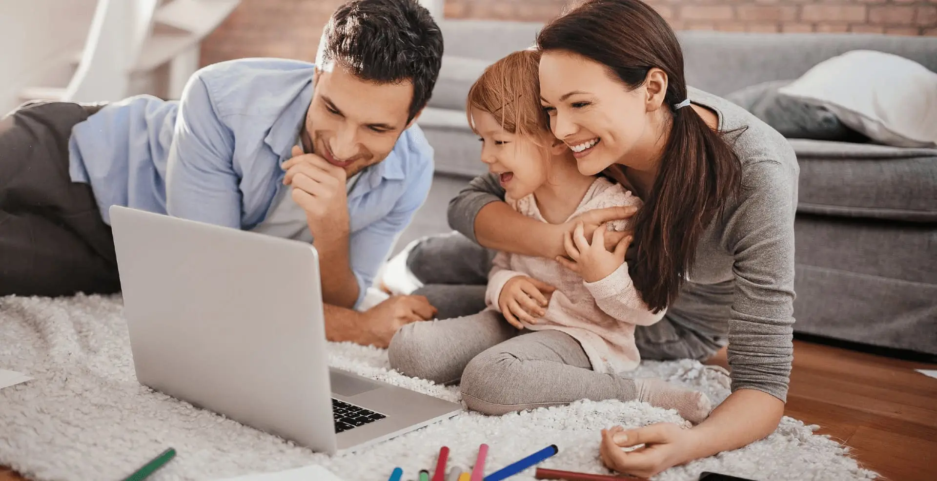 Eine junge Familie sitzt gemeinsam vor dem Laptop
