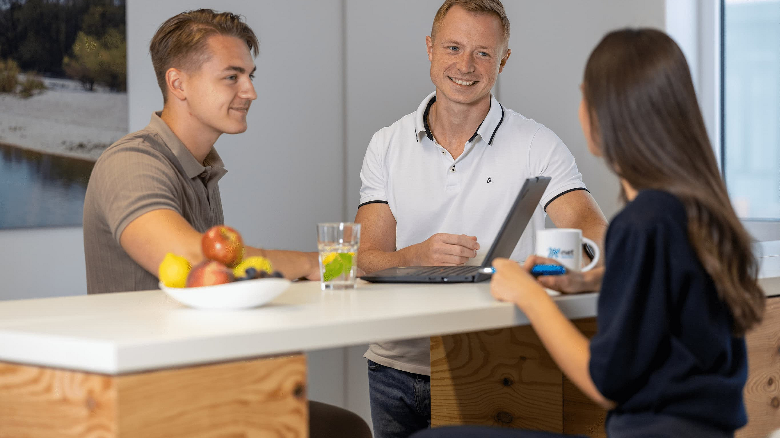 Drei Kollegen stehen bei M-net gemeinsam am Stehtisch, diskutierend