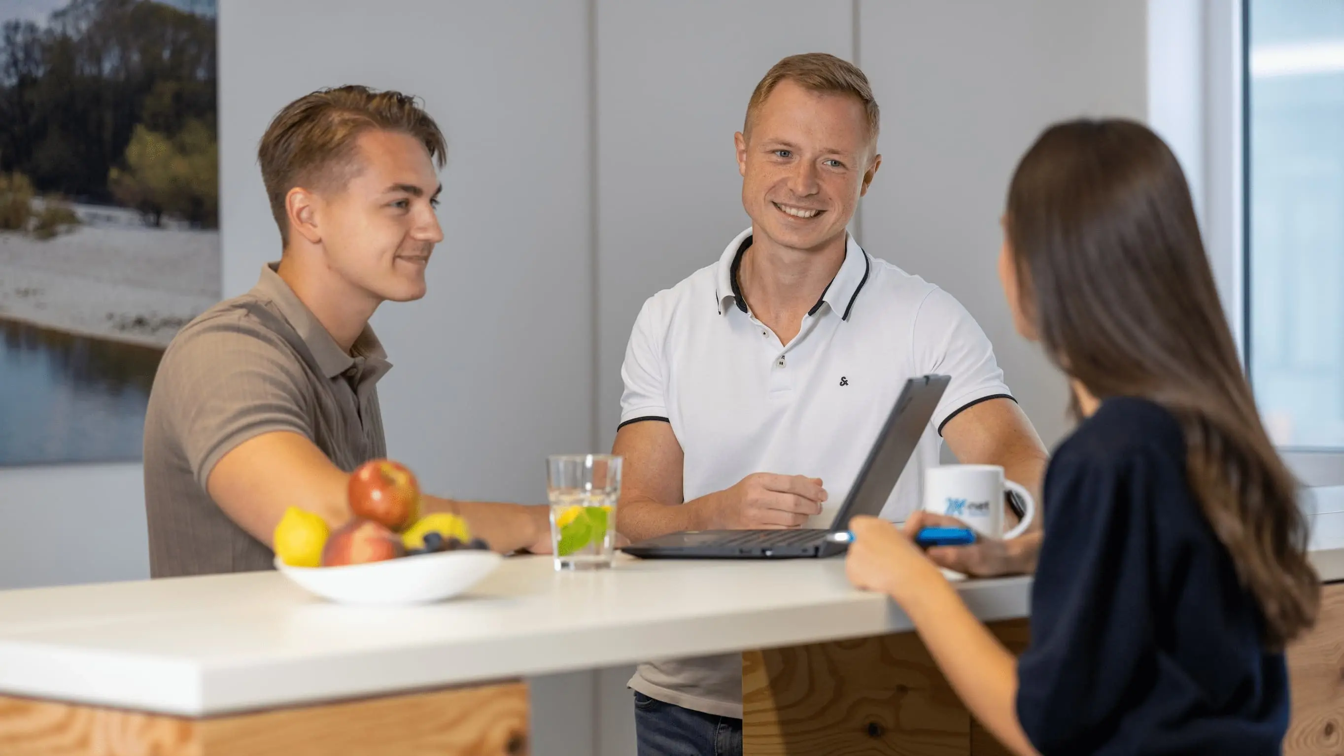 Drei Kollegen stehen bei M-net gemeinsam am Stehtisch, diskutierend