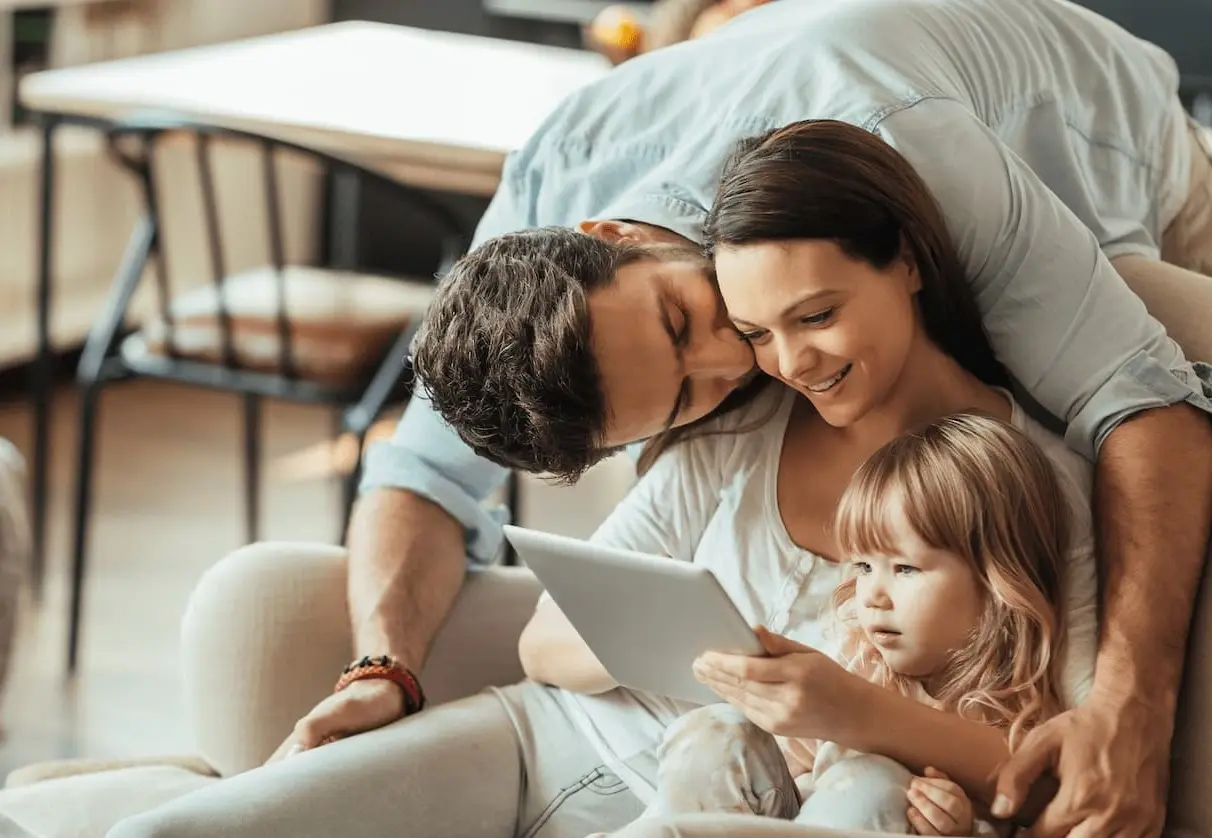 Eine Familie sitzt zuhause gemeinsam am Tablet
