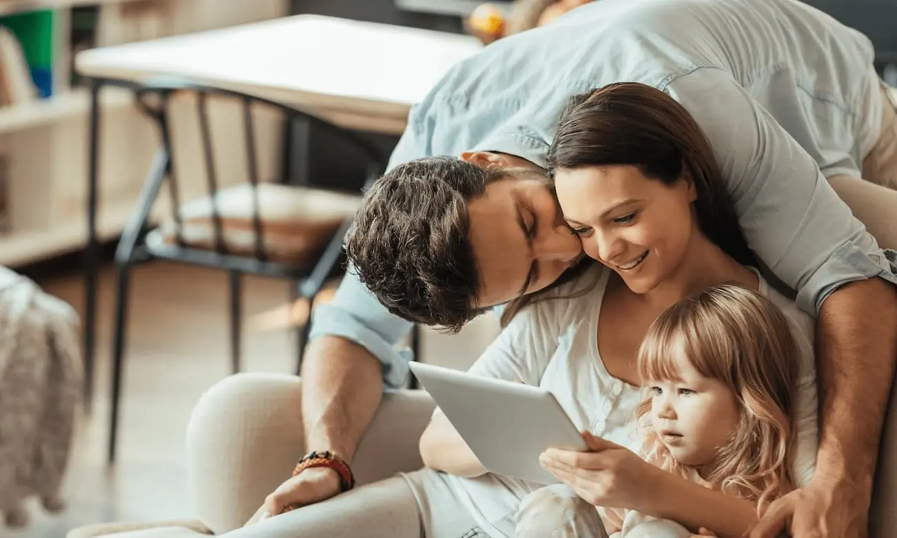 Eine Familie sitzt zuhause gemeinsam am Tablet