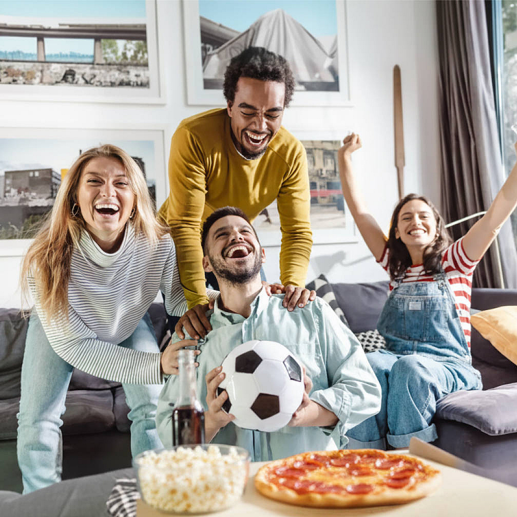 Menschen schauen zuhause jubelnd Fußball