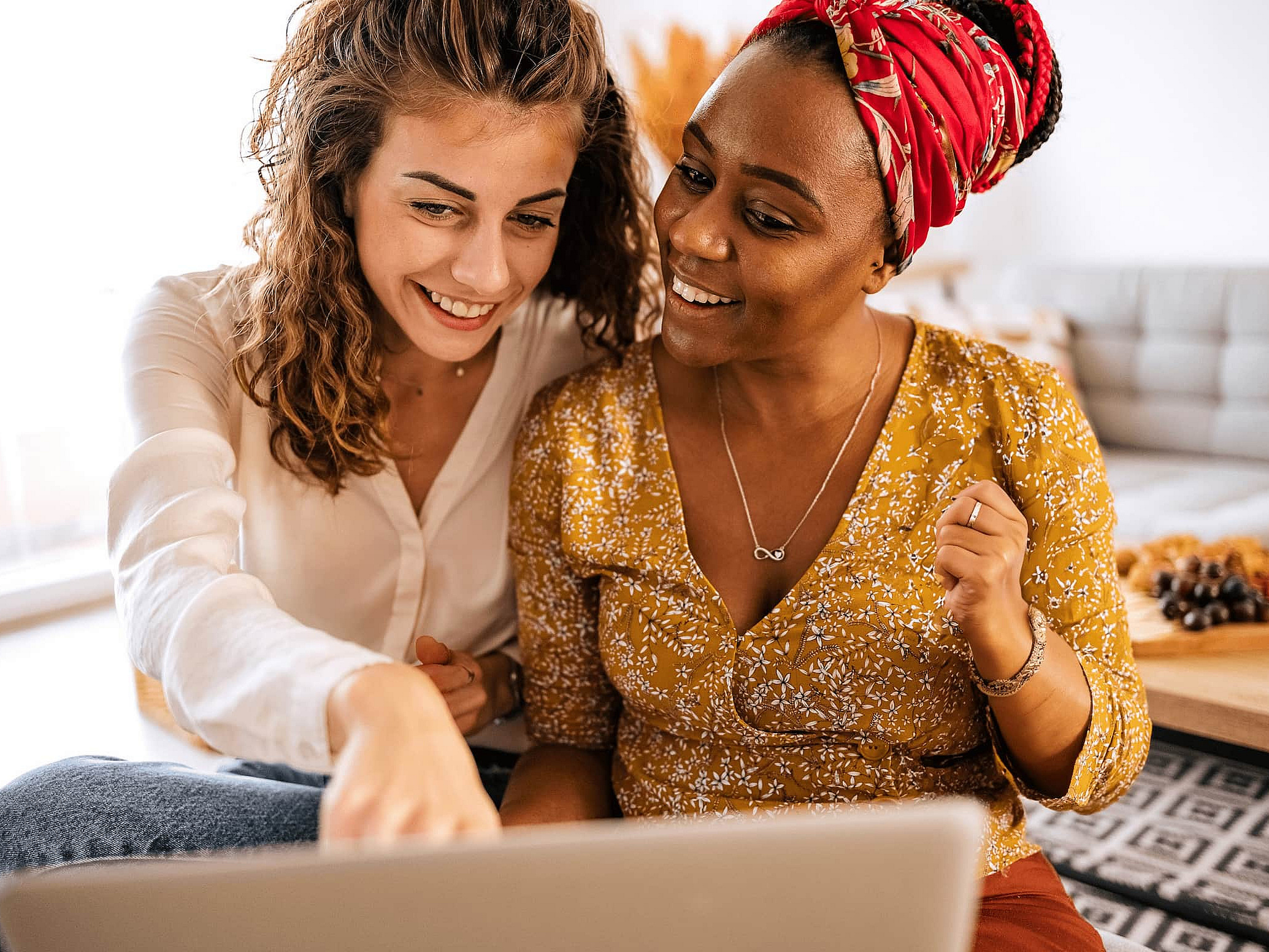 Zwei Frauen sitzen gemeinsam vor einem Laptop