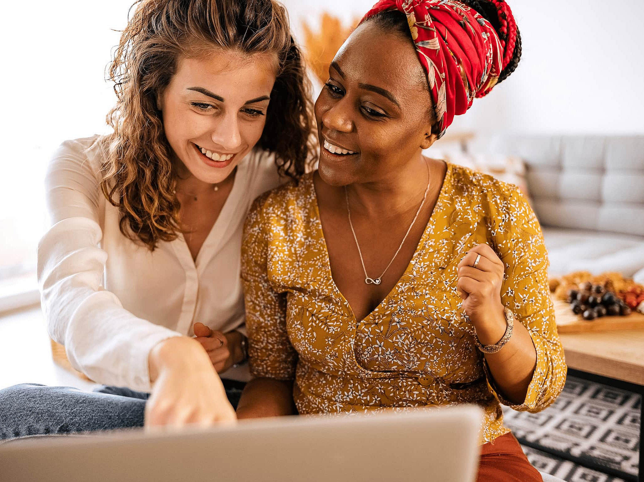 Zwei Frauen sitzen gemeinsam vor einem Laptop