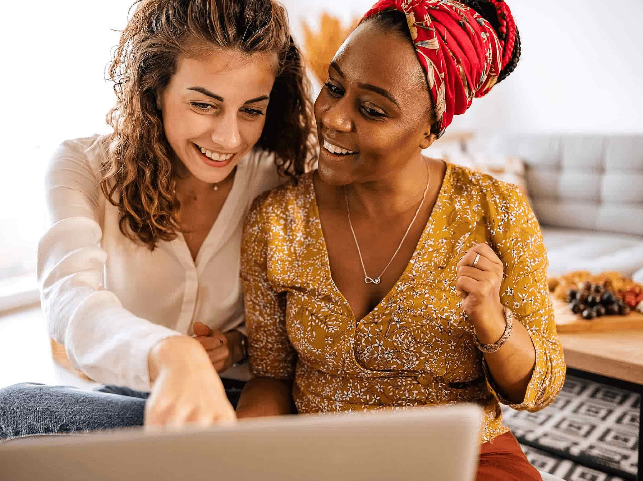 Zwei Frauen sitzen gemeinsam vor einem Laptop