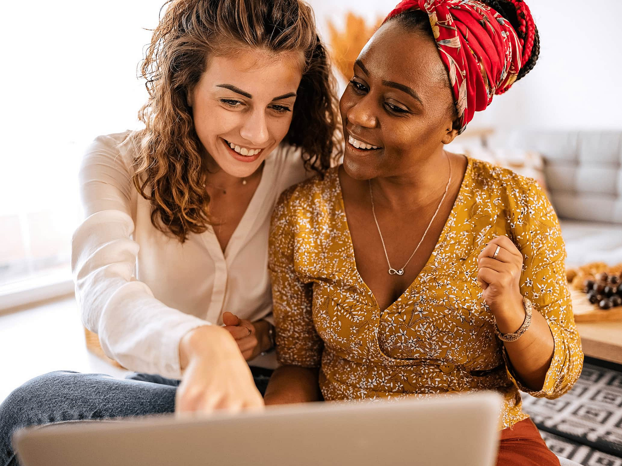 Zwei Frauen sitzen gemeinsam vor einem Laptop