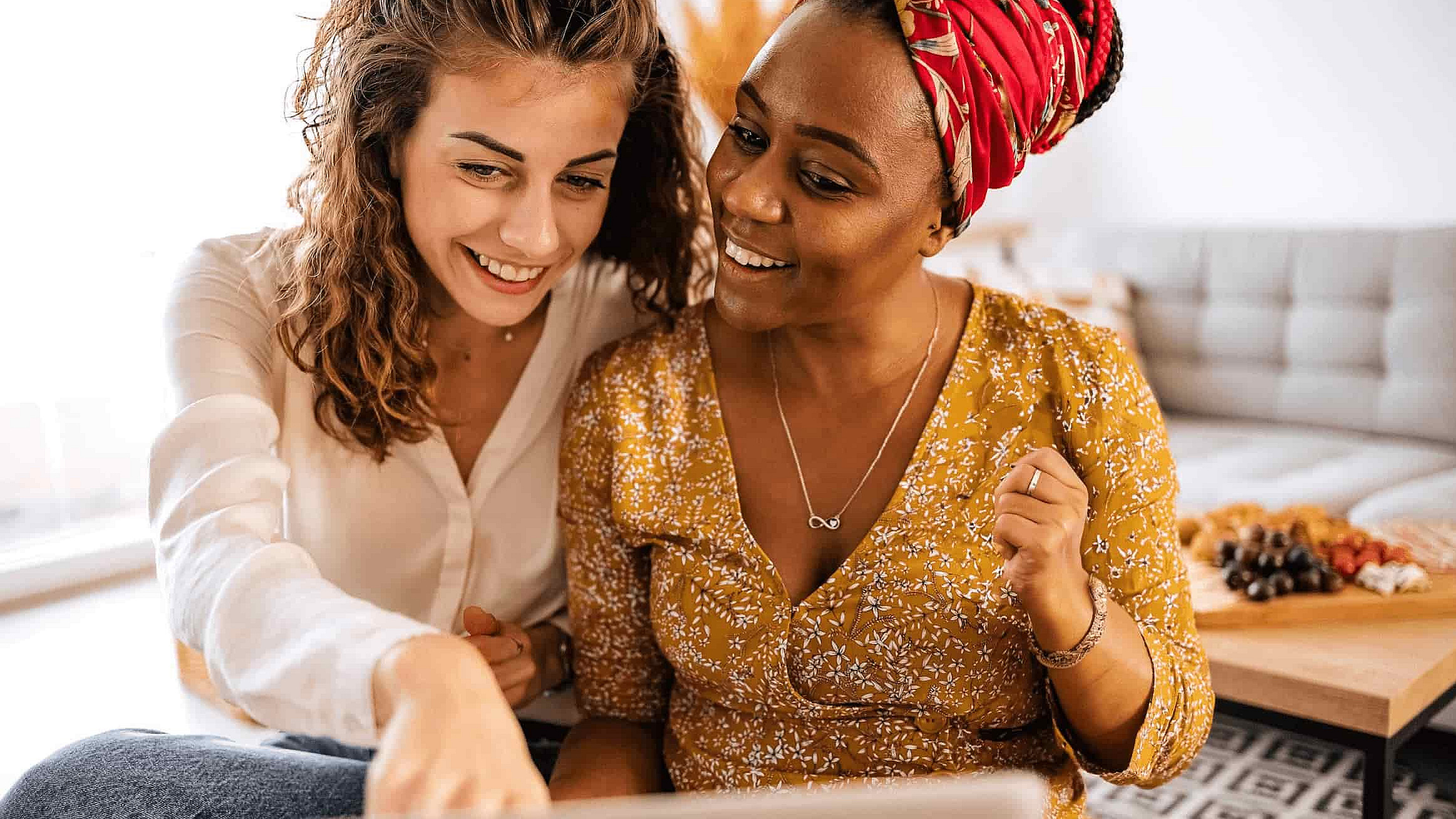 Zwei Frauen sitzen gemeinsam vor dem Laptop