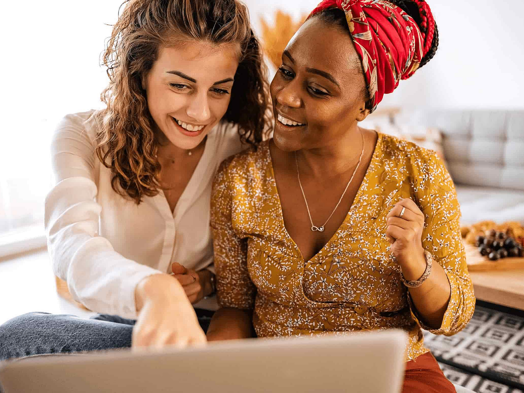 Zwei Frauen sitzen gemeinsam vor einem Laptop