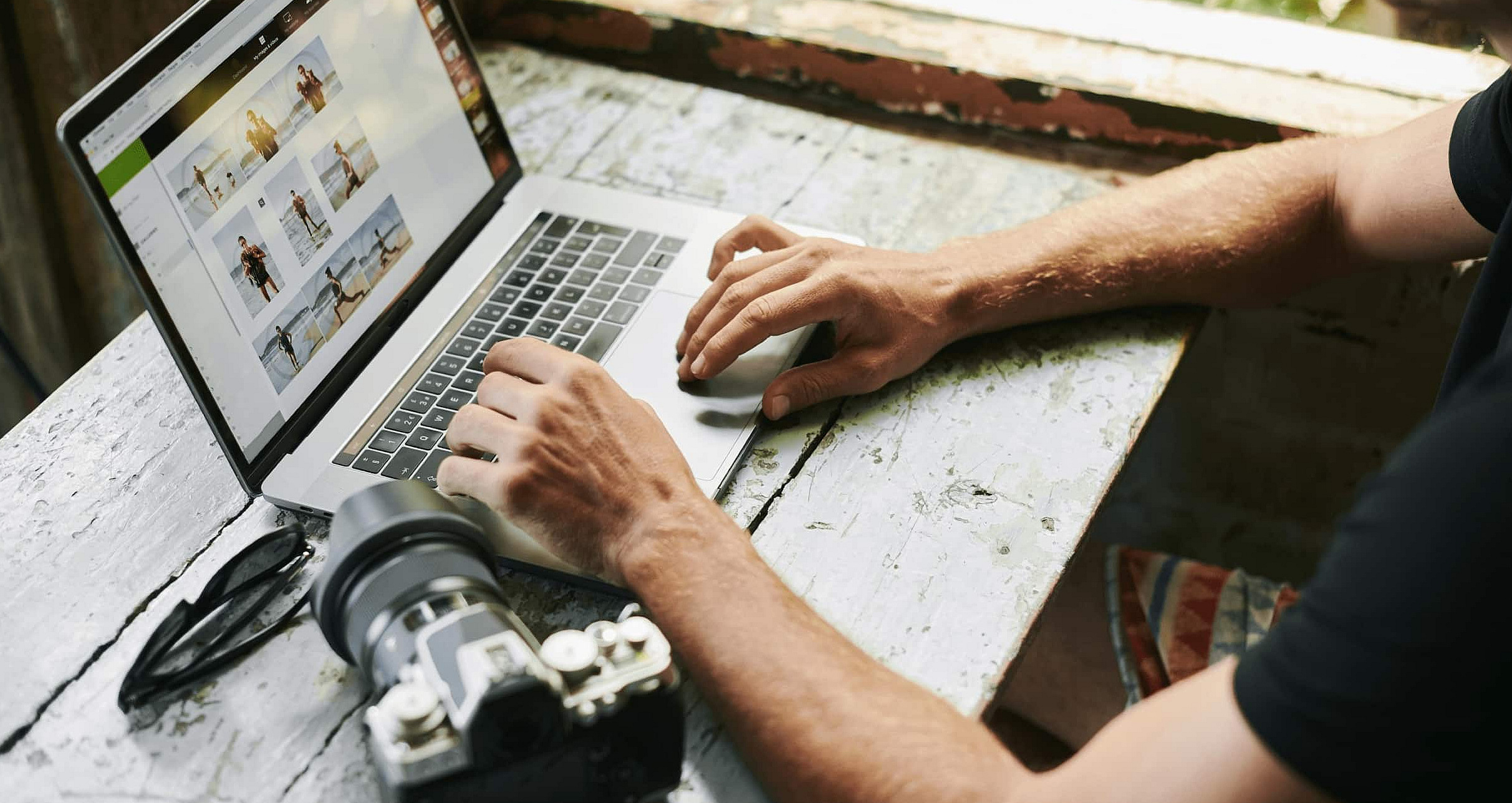 Ein Fotograf bearbeitet am Laptop Bilder, neben sich liegt seine Kamera